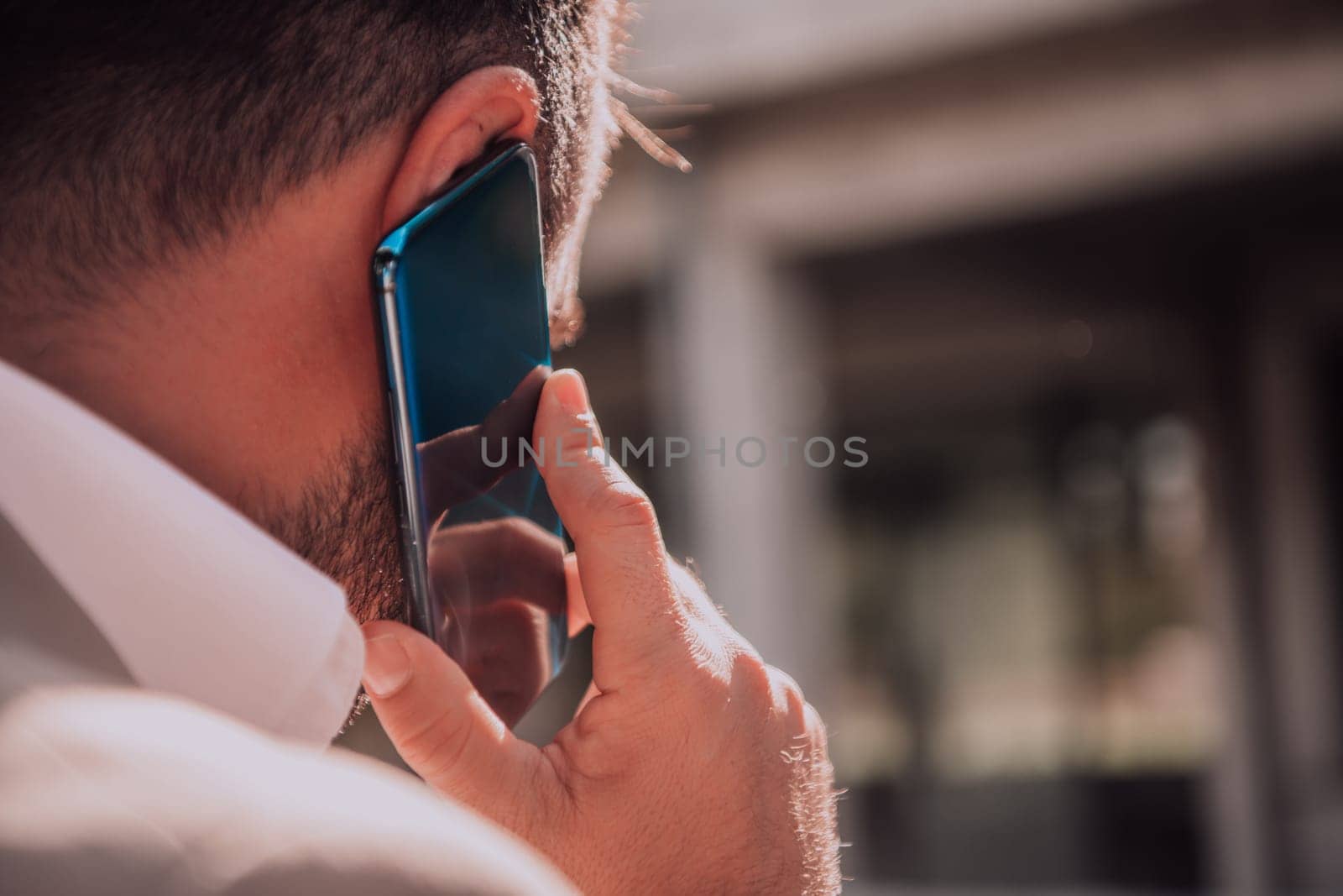 A businessman using his smartphone outdoors, showcasing the seamless integration of technology and mobility in modern professional life. by dotshock