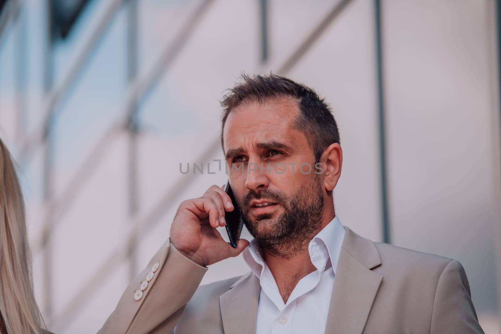 A businessman using his smartphone outdoors, showcasing the seamless integration of technology and mobility in modern professional life. by dotshock