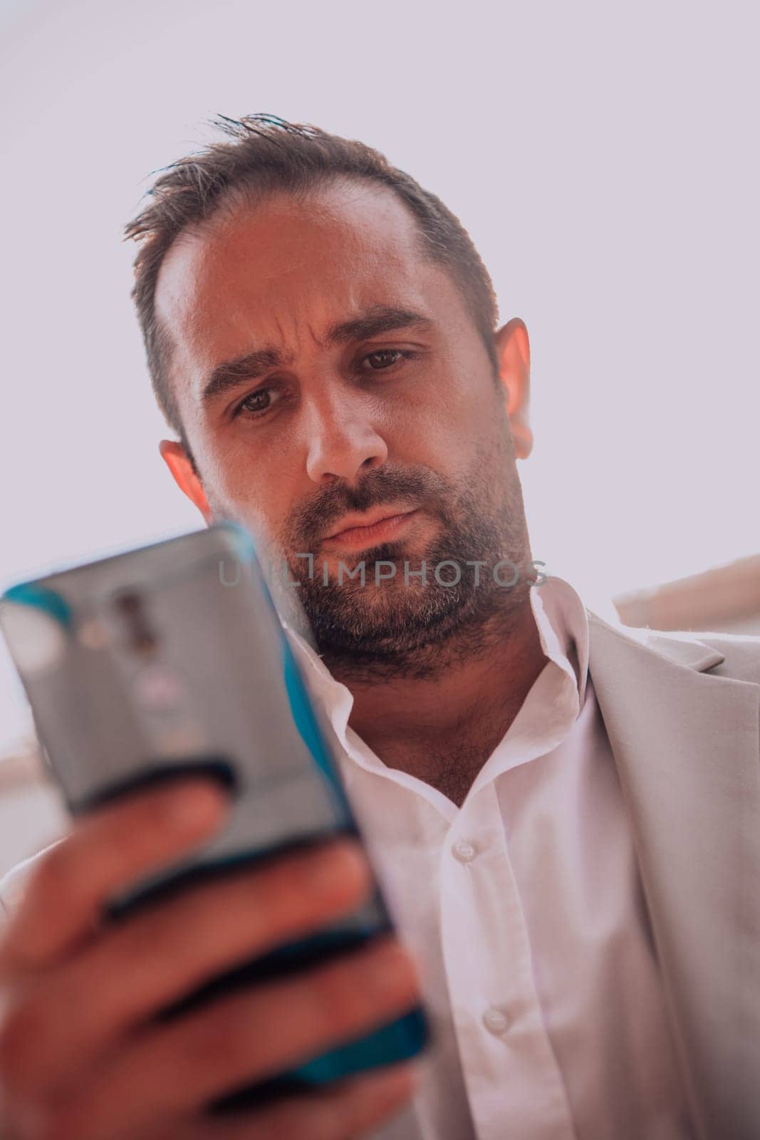 A businessman using his smartphone outdoors, showcasing the seamless integration of technology and mobility in modern professional life. by dotshock