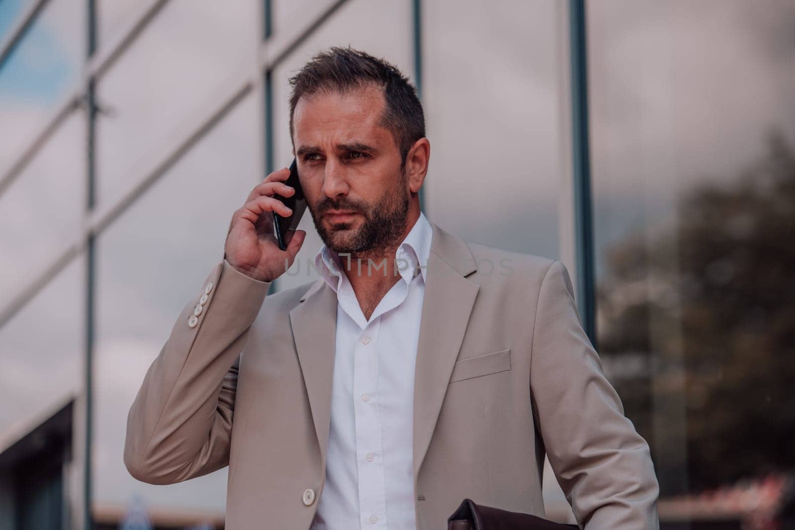 A businessman using his smartphone outdoors, showcasing the seamless integration of technology and mobility in modern professional life. by dotshock