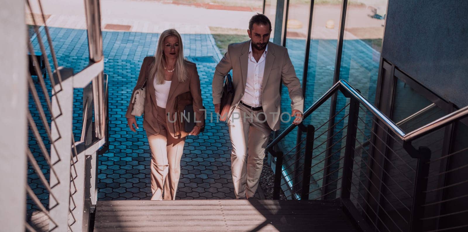 Modern business couple after a long day's work, walking together towards the comfort of their home, embodying the perfect blend of professional success and personal contentment. by dotshock