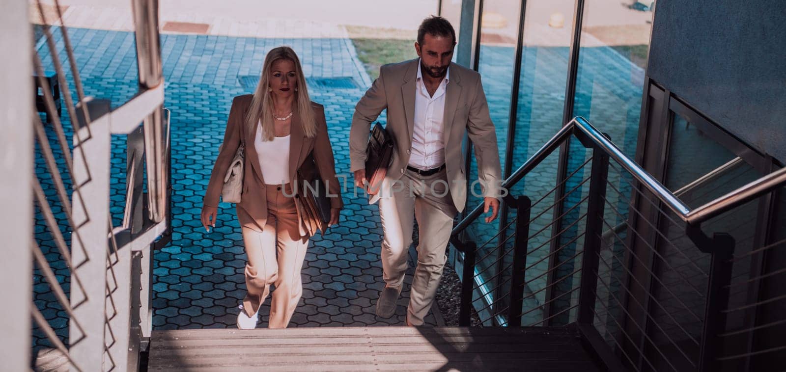 Modern business couple after a long day's work, walking together towards the comfort of their home, embodying the perfect blend of professional success and personal contentment. by dotshock