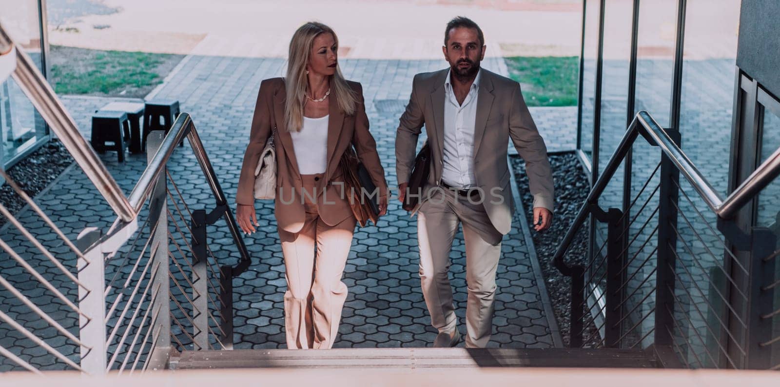Modern business couple after a long day's work, walking together towards the comfort of their home, embodying the perfect blend of professional success and personal contentment. by dotshock