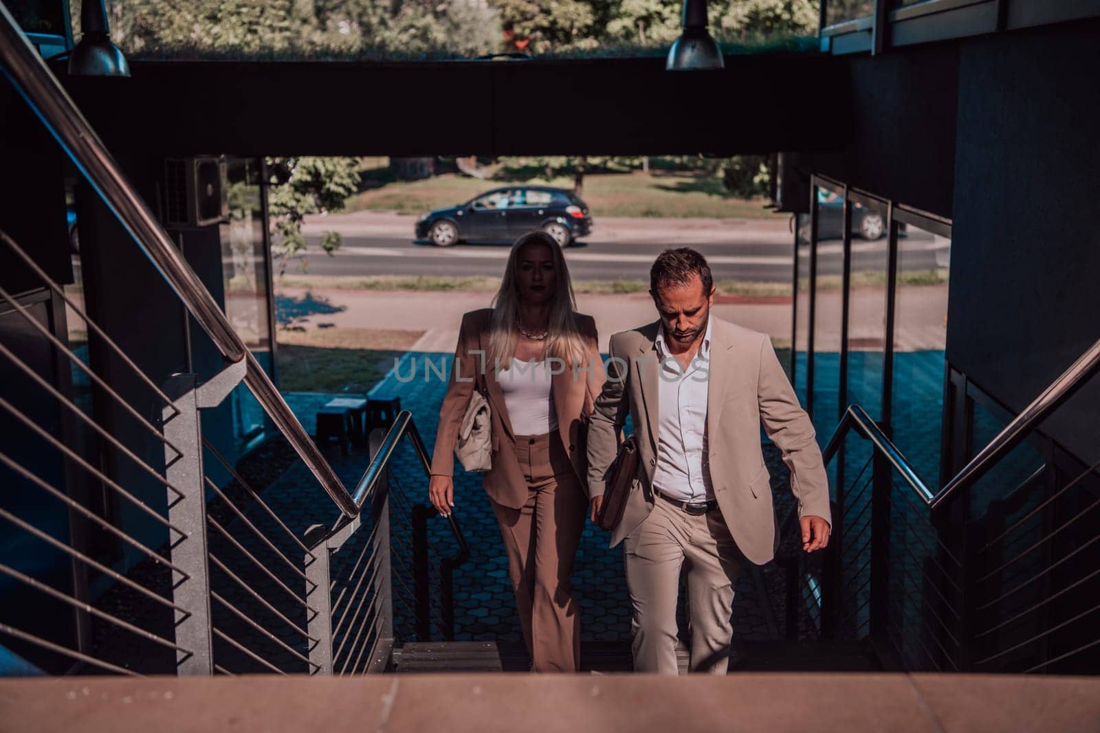 Modern business couple after a long day's work, walking together towards the comfort of their home, embodying the perfect blend of professional success and personal contentment. by dotshock