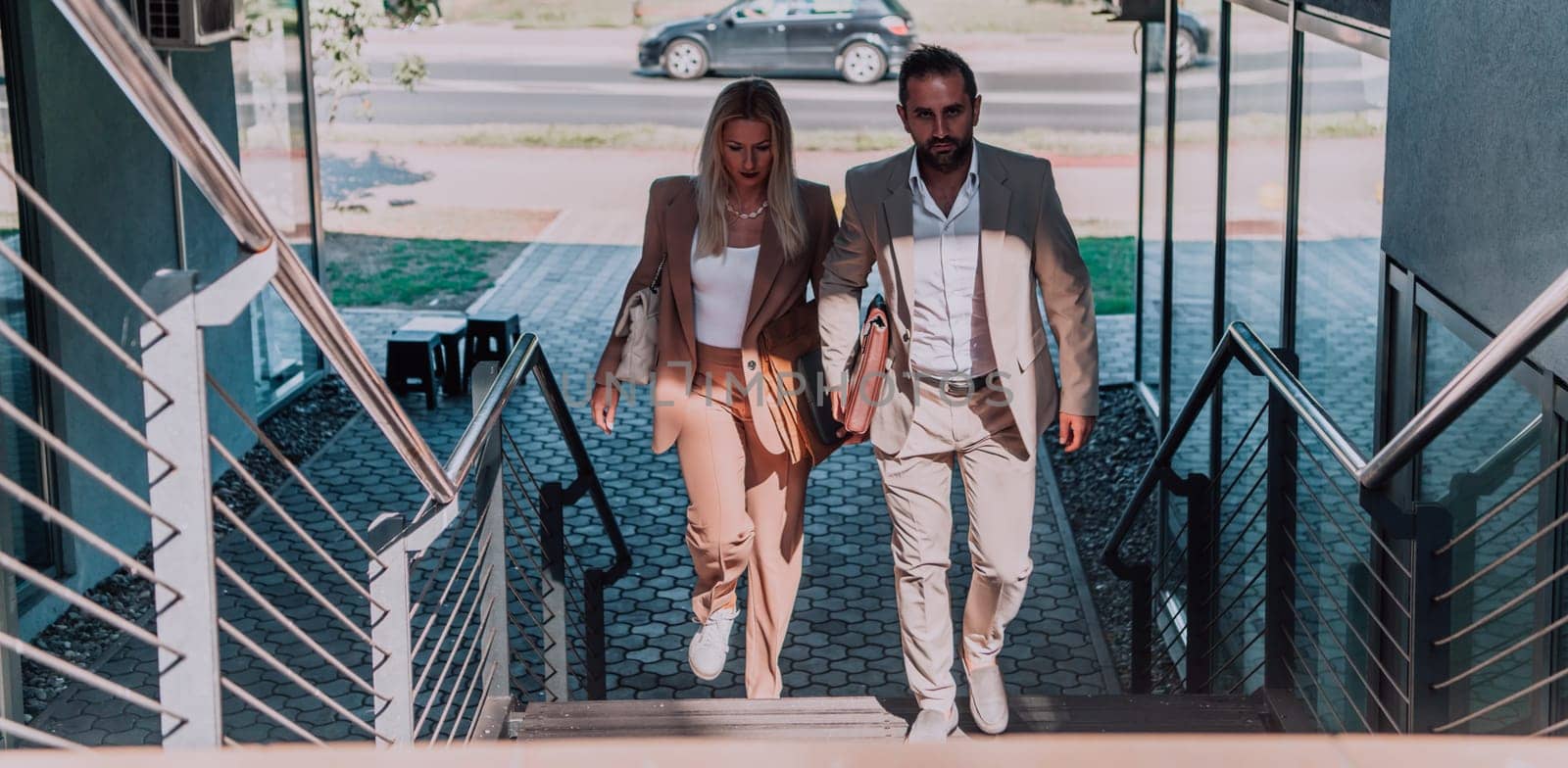 Modern business couple after a long day's work, walking together towards the comfort of their home, embodying the perfect blend of professional success and personal contentment. by dotshock