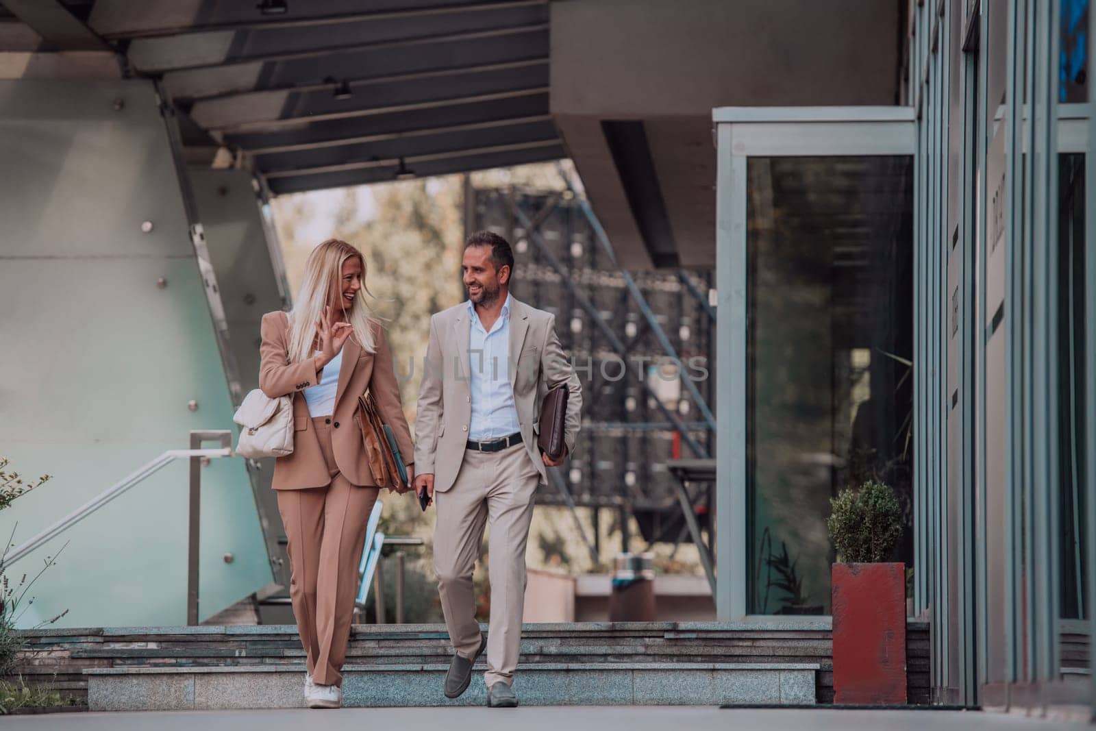 Modern business couple after a long day's work, walking together towards the comfort of their home, embodying the perfect blend of professional success and personal contentment. by dotshock