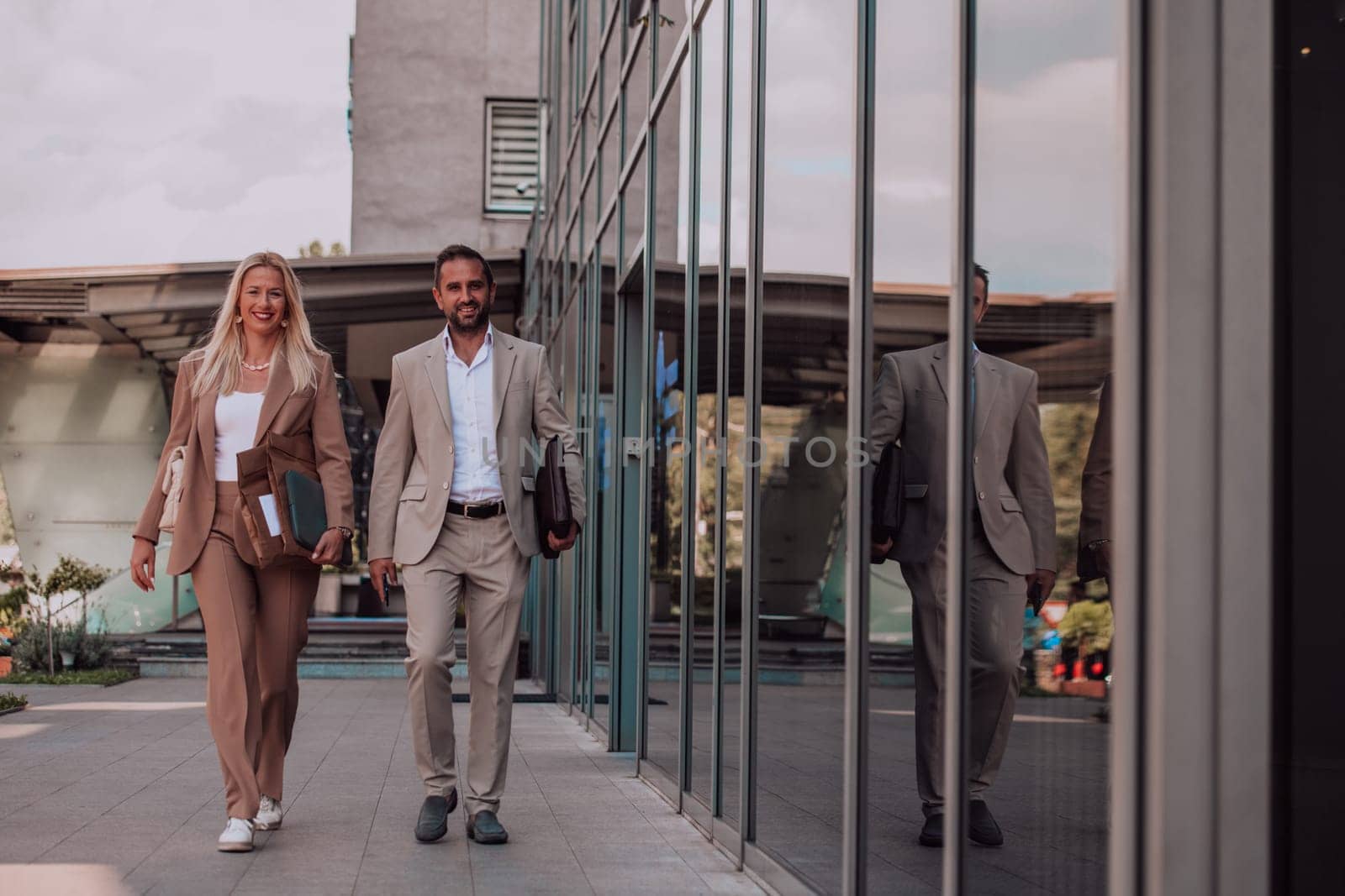 Modern business couple after a long day's work, walking together towards the comfort of their home, embodying the perfect blend of professional success and personal contentment. by dotshock