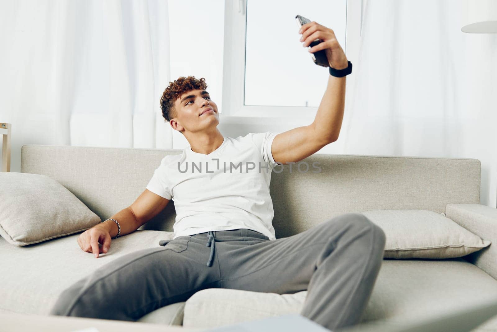 man interior cyberspace modern person sports blogger sofa text phone cellphone blissful using smartphone curly student