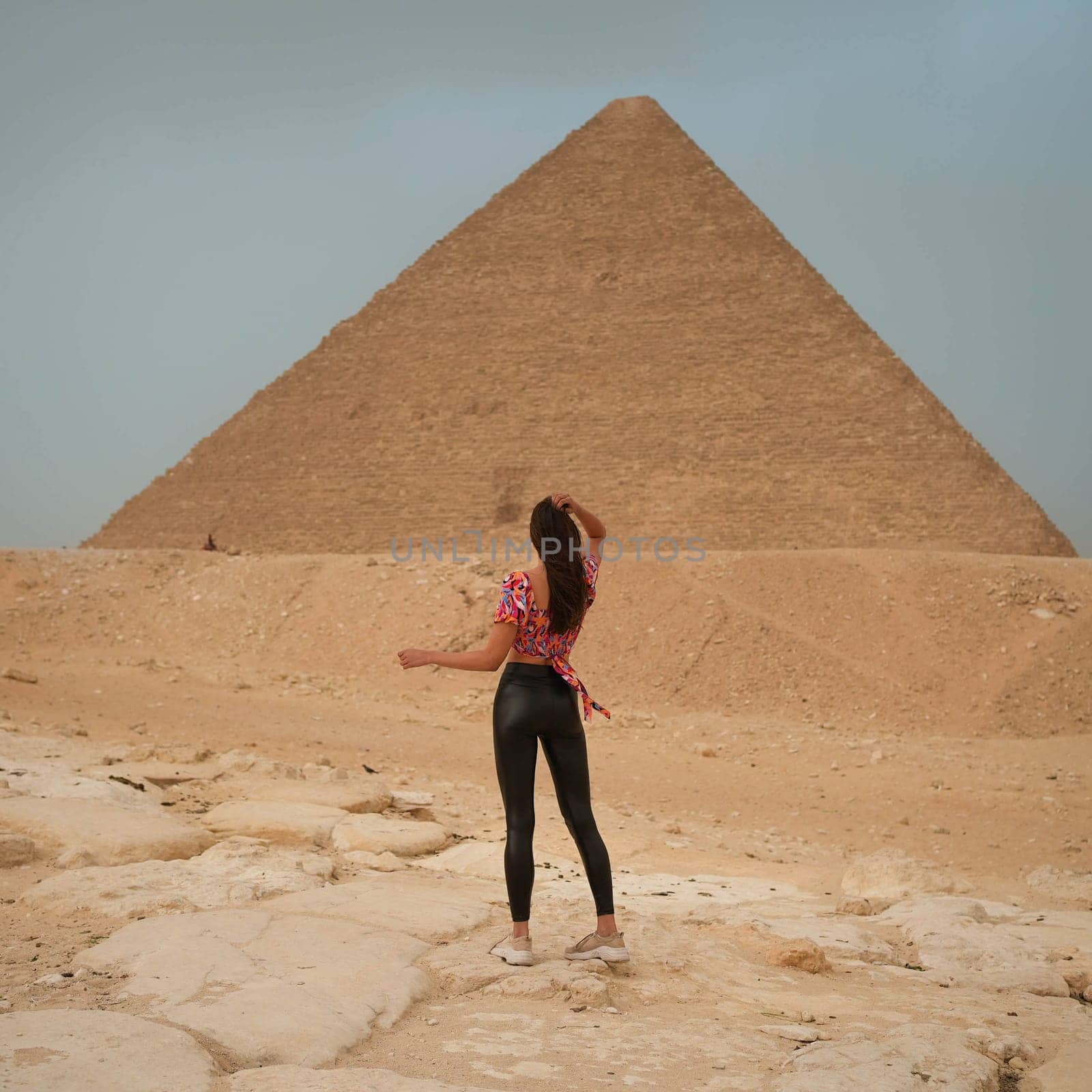 Tall pretty model girl in leather pants standing in front of the Pyramid of Giza. High quality photo