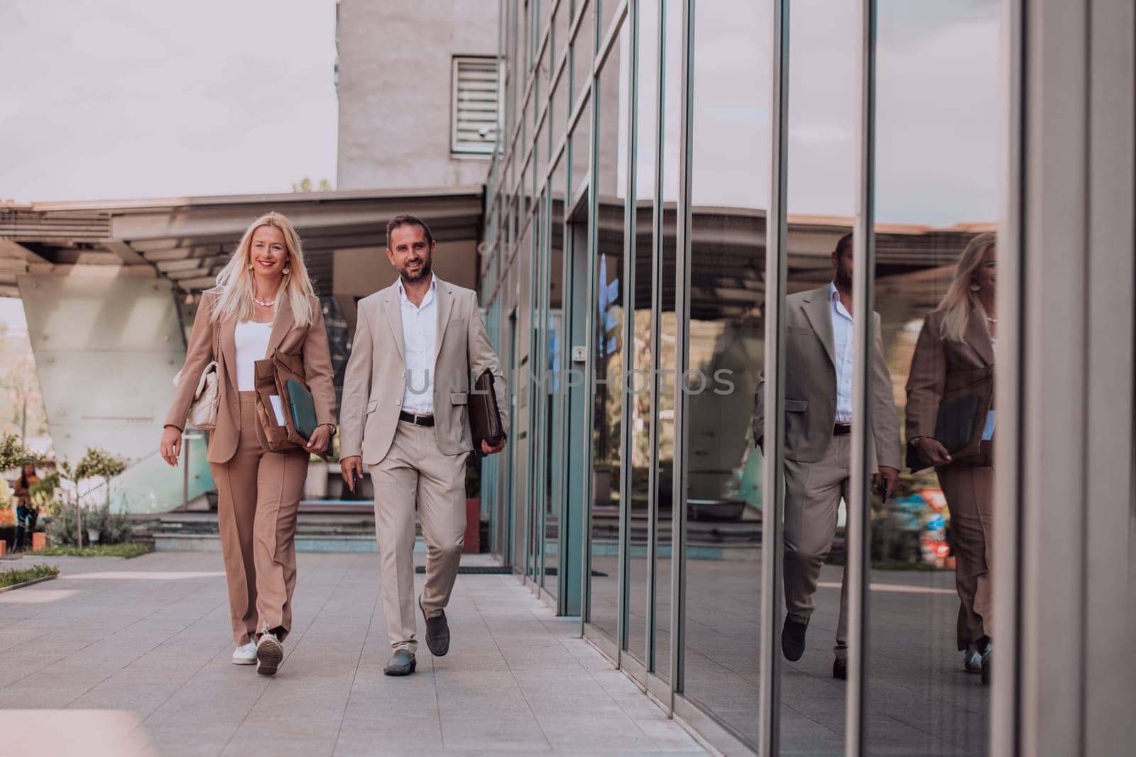 Modern business couple after a long day's work, walking together towards the comfort of their home, embodying the perfect blend of professional success and personal contentment. by dotshock