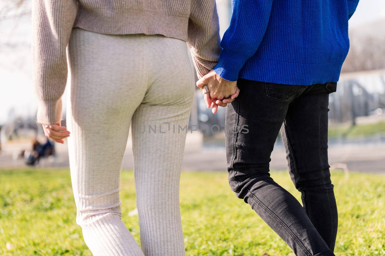 two unrecognizable women walking together holding hands in a city park, concept of freedom and love between people of the same sex