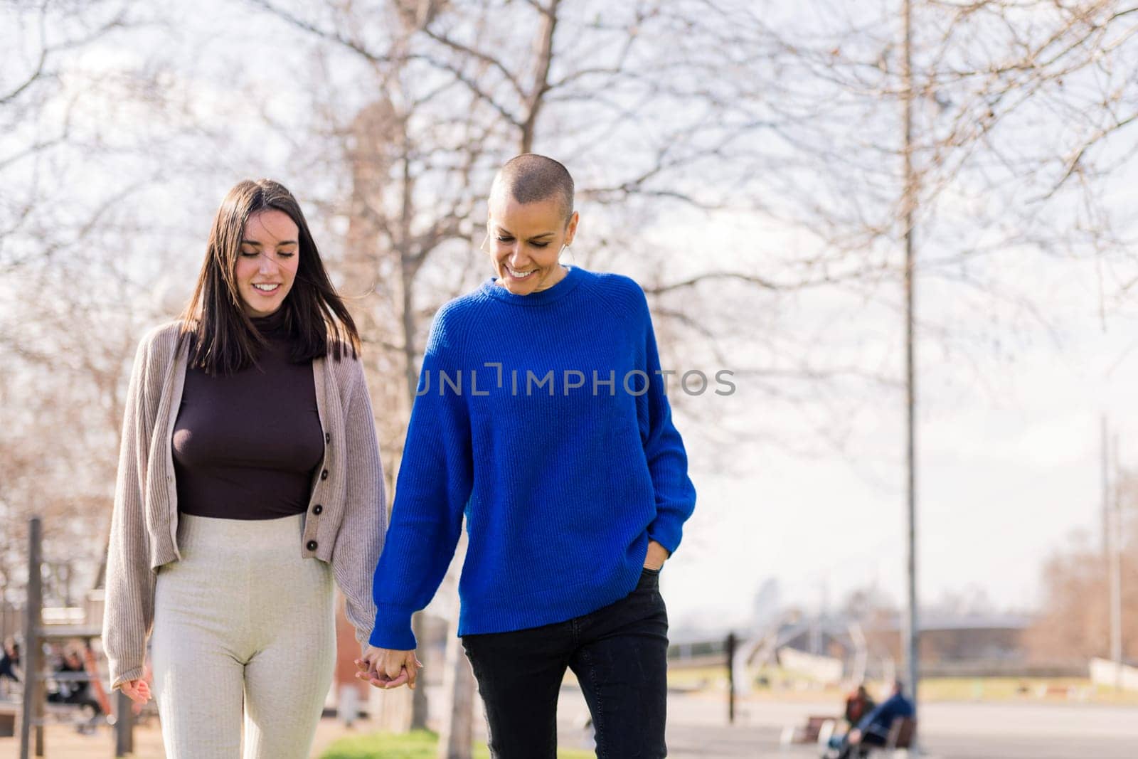 lesbian couple of two young women smiling happy taking a romantic walk in a city park, concept of freedom and love between people of the same sex