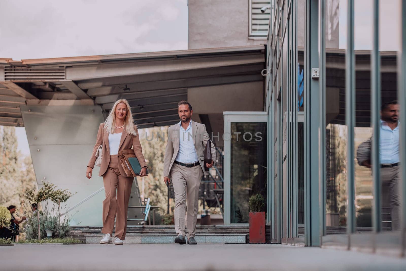Modern business couple after a long day's work, walking together towards the comfort of their home, embodying the perfect blend of professional success and personal contentment. by dotshock
