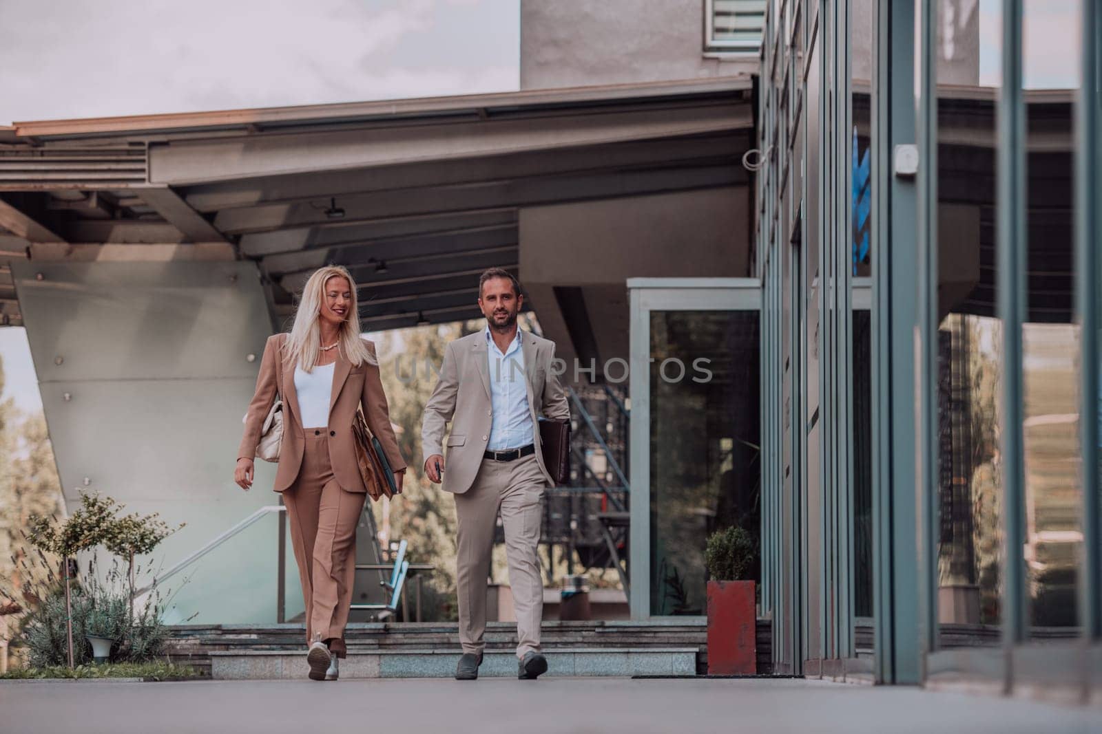 Modern business couple after a long day's work, walking together towards the comfort of their home, embodying the perfect blend of professional success and personal contentment. by dotshock