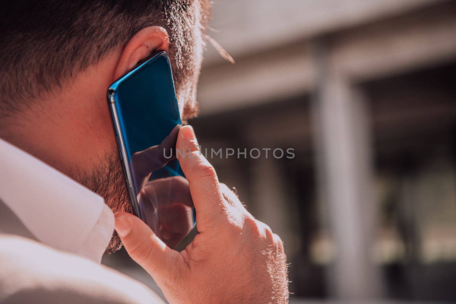 A businessman using his smartphone outdoors, showcasing the seamless integration of technology and mobility in modern professional life. by dotshock