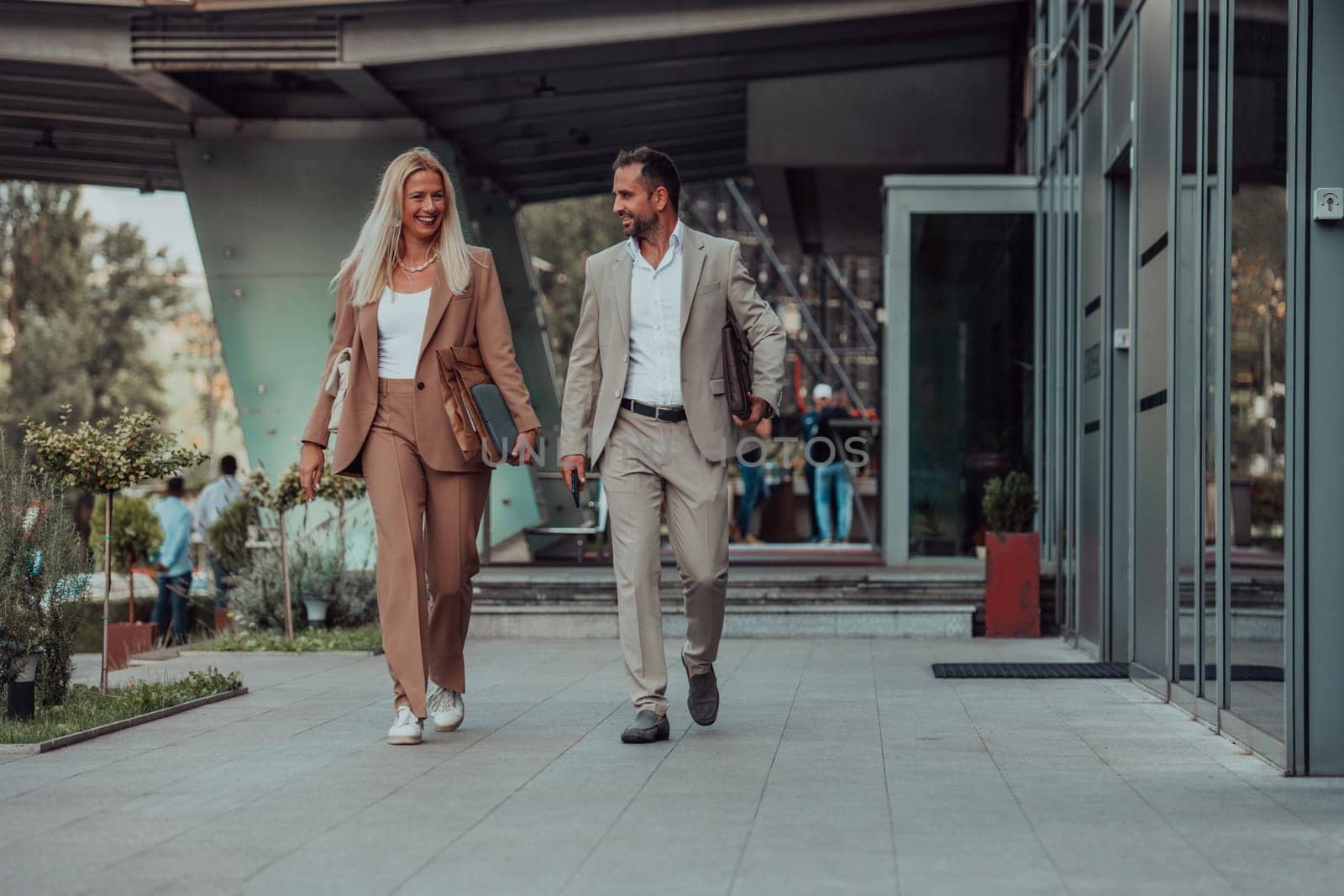 Modern business couple after a long day's work, walking together towards the comfort of their home, embodying the perfect blend of professional success and personal contentment. by dotshock