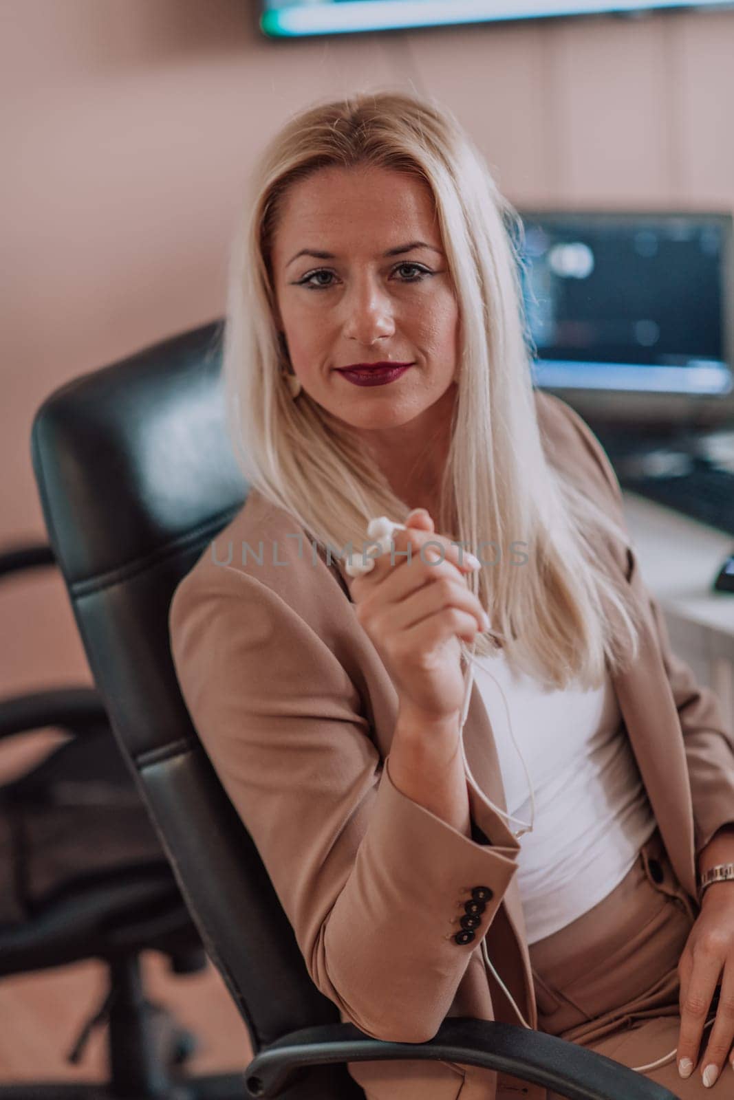 A businesswoman sitting in a programmer's office surrounded by computers, showing her expertise and dedication to technology