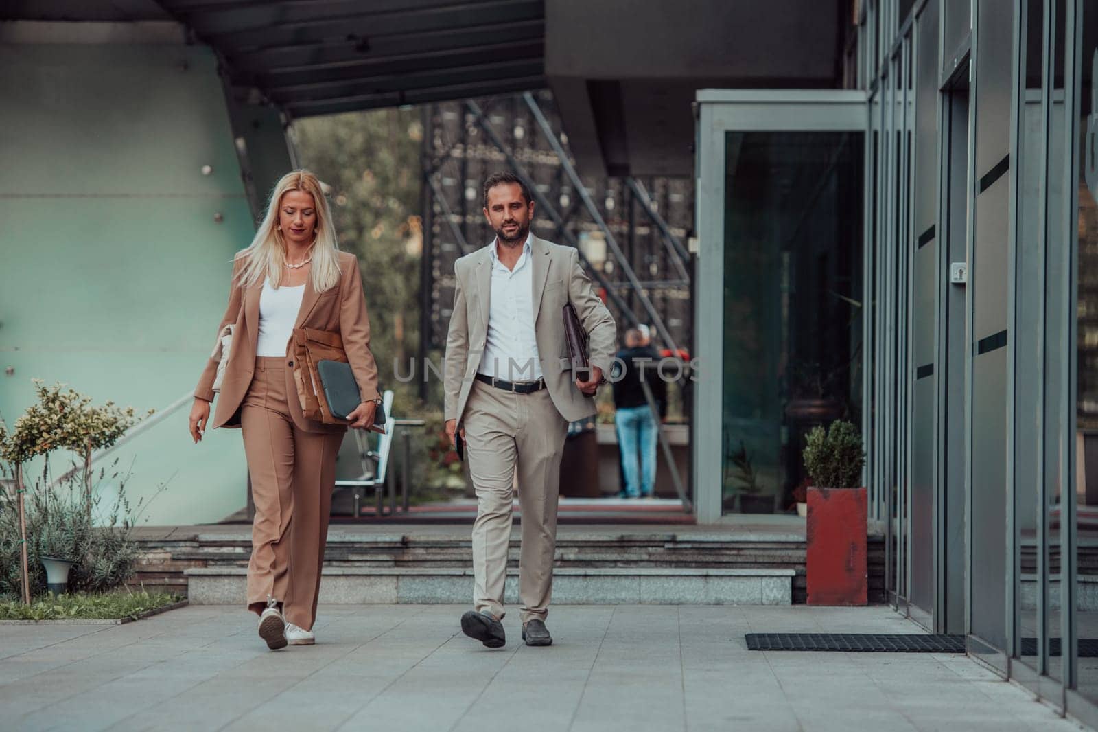 Modern business couple after a long day's work, walking together towards the comfort of their home, embodying the perfect blend of professional success and personal contentment. by dotshock