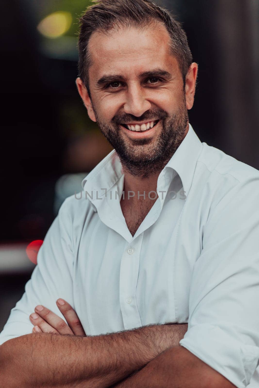 A successful businessman in a white shirt with crossed arms posing outdoors by dotshock