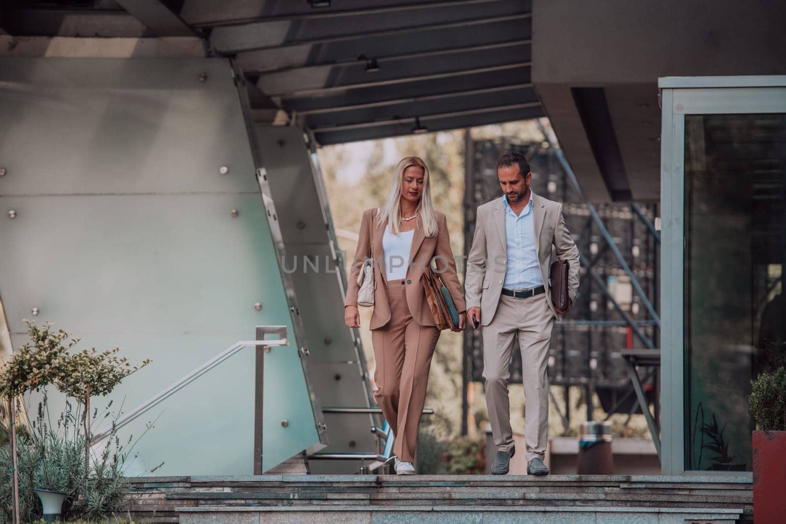 Modern business couple after a long day's work, walking together towards the comfort of their home, embodying the perfect blend of professional success and personal contentment. by dotshock