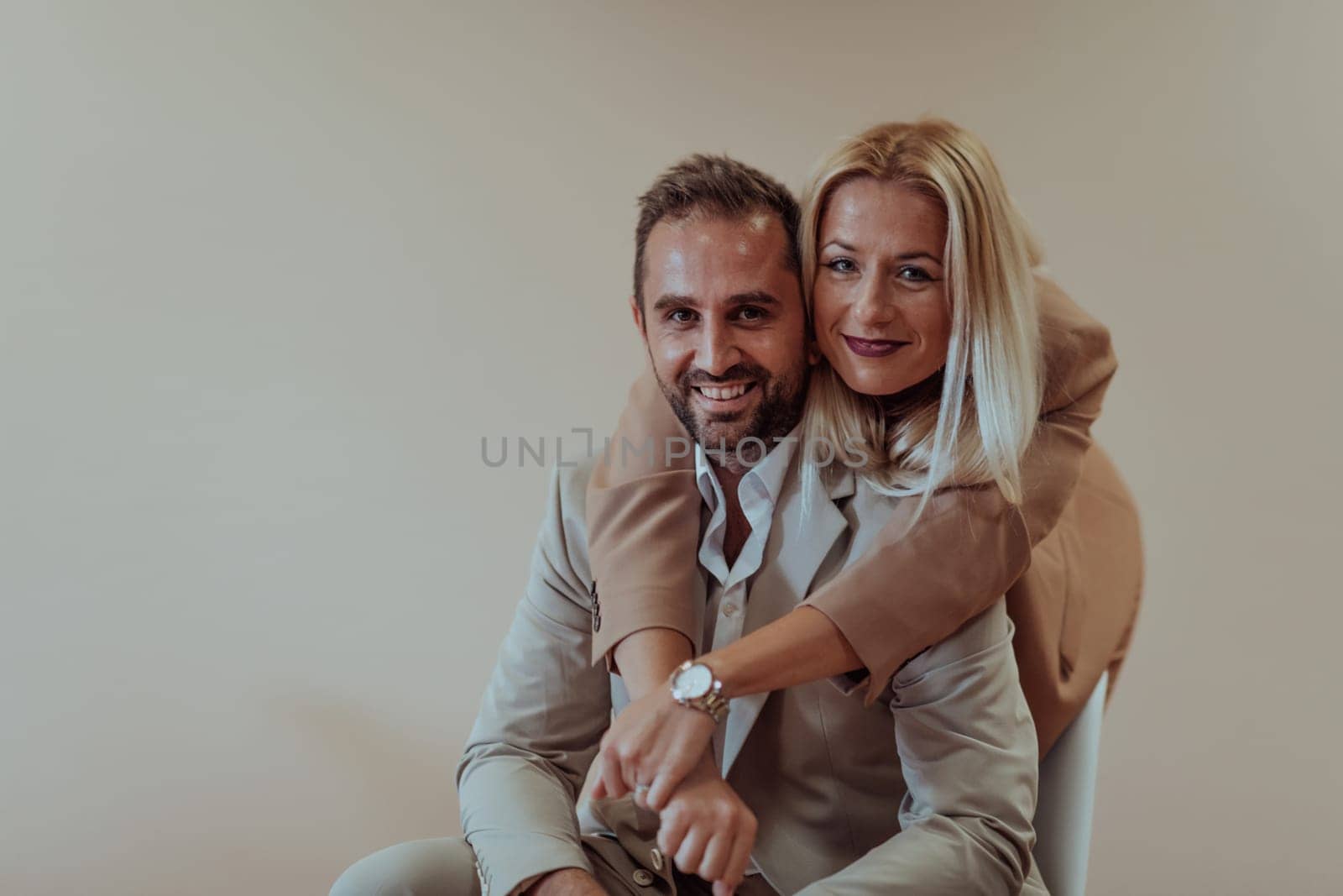 A business couple posing for a photograph together against a beige backdrop, capturing their professional partnership and creating a timeless image of unity and success. by dotshock