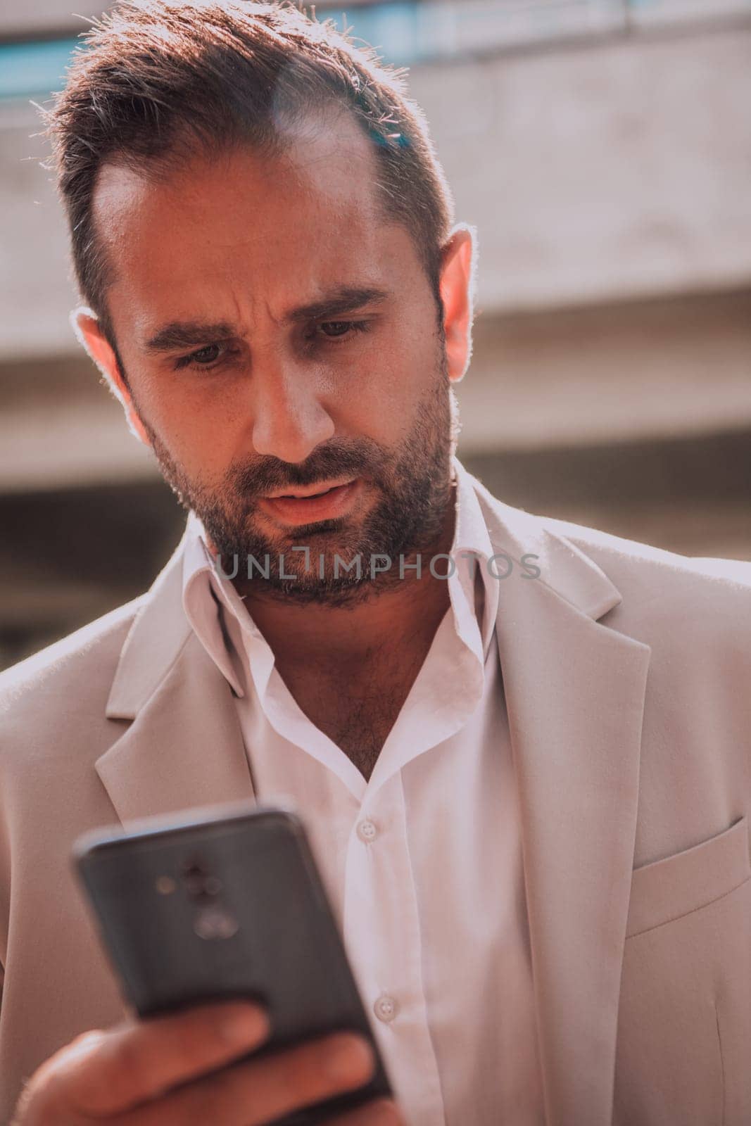 A businessman using his smartphone outdoors, showcasing the seamless integration of technology and mobility in modern professional life. by dotshock