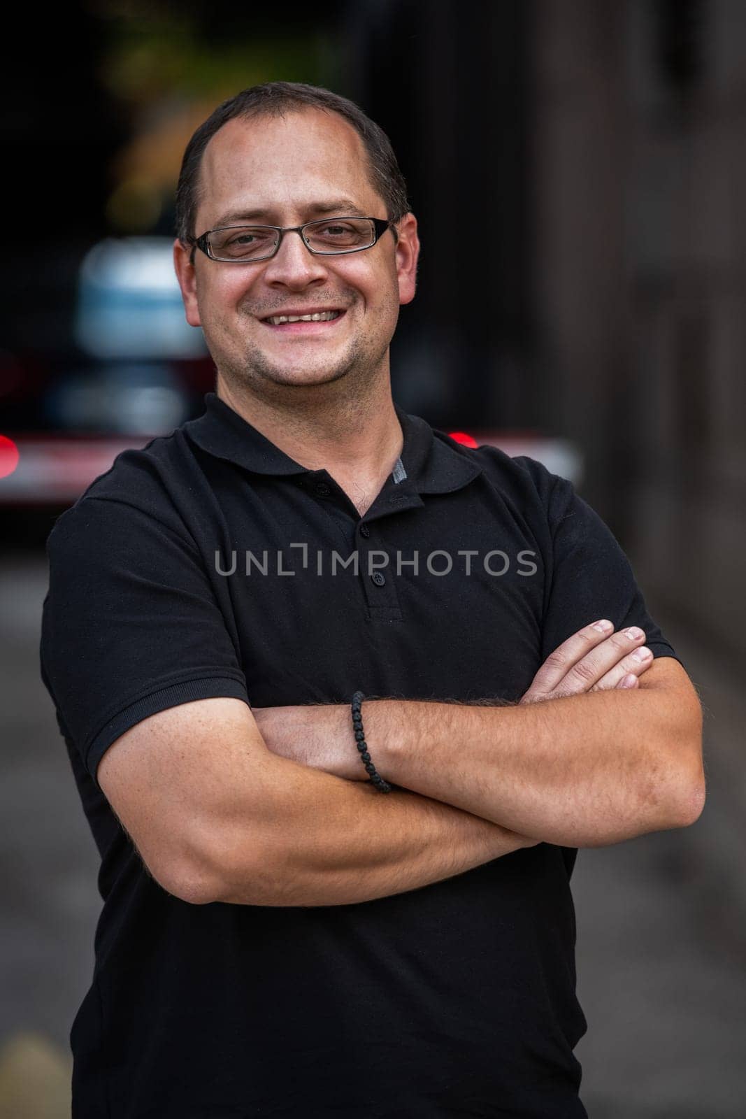 A successful businessman with crossed arms, posing outdoors. High quality photo