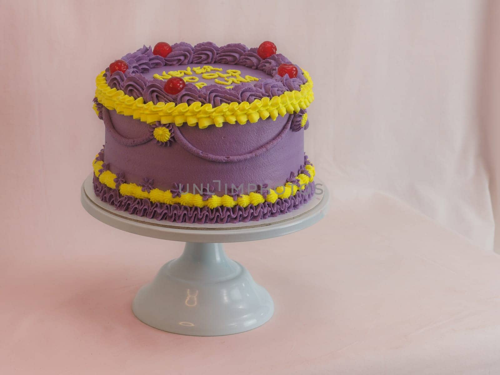 frosted icing violet yellow classic cilindrical cake on studio by verbano