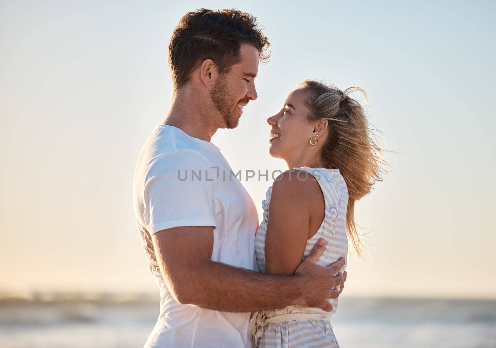 Couple, travel and hug with love and beach holiday, romantic vacation and happy together at sunrise. Man, woman and care with adventure by the ocean, outdoor and nature for bonding and romance. by YuriArcurs