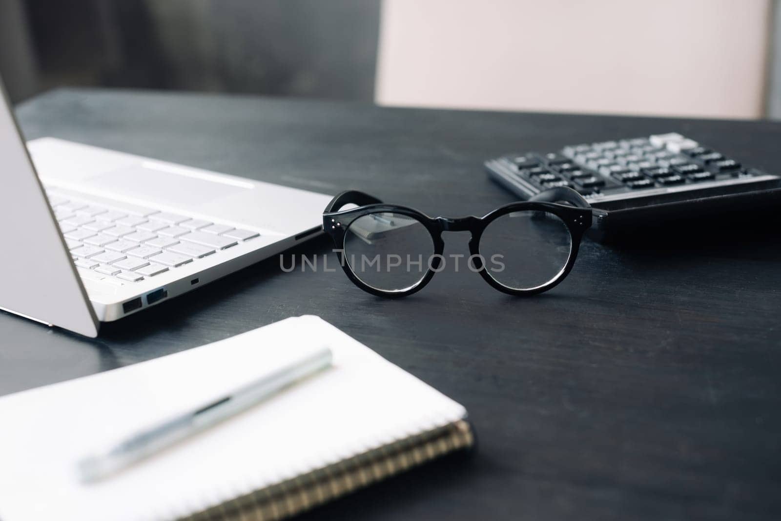 Professional Accounting Setting: Office Desk Featuring Calculator, Laptop, and Glasses - Depicting Finance, Business, and Modern Accountancy Concepts.