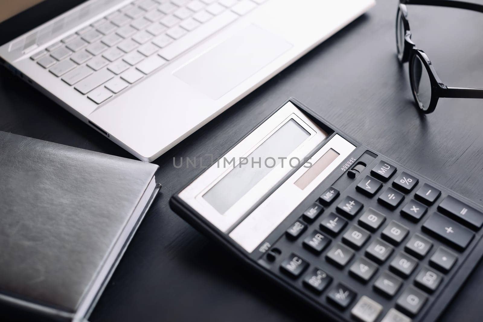 Accountant's Workspace: Office Desk with Laptop, Calculator, and Glasses - Depicting Modern Business, Finance, and Accounting Practices.