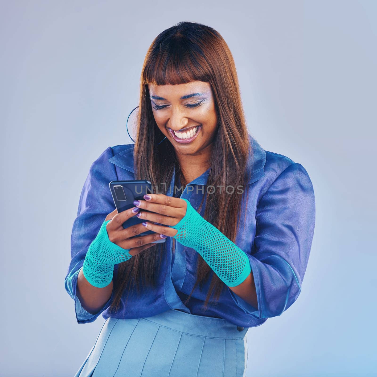 Woman, phone and laughing for funny joke, meme or social media isolated against a studio background. Happy female model smiling and laugh in fashion on mobile smartphone for networking with fun humor.