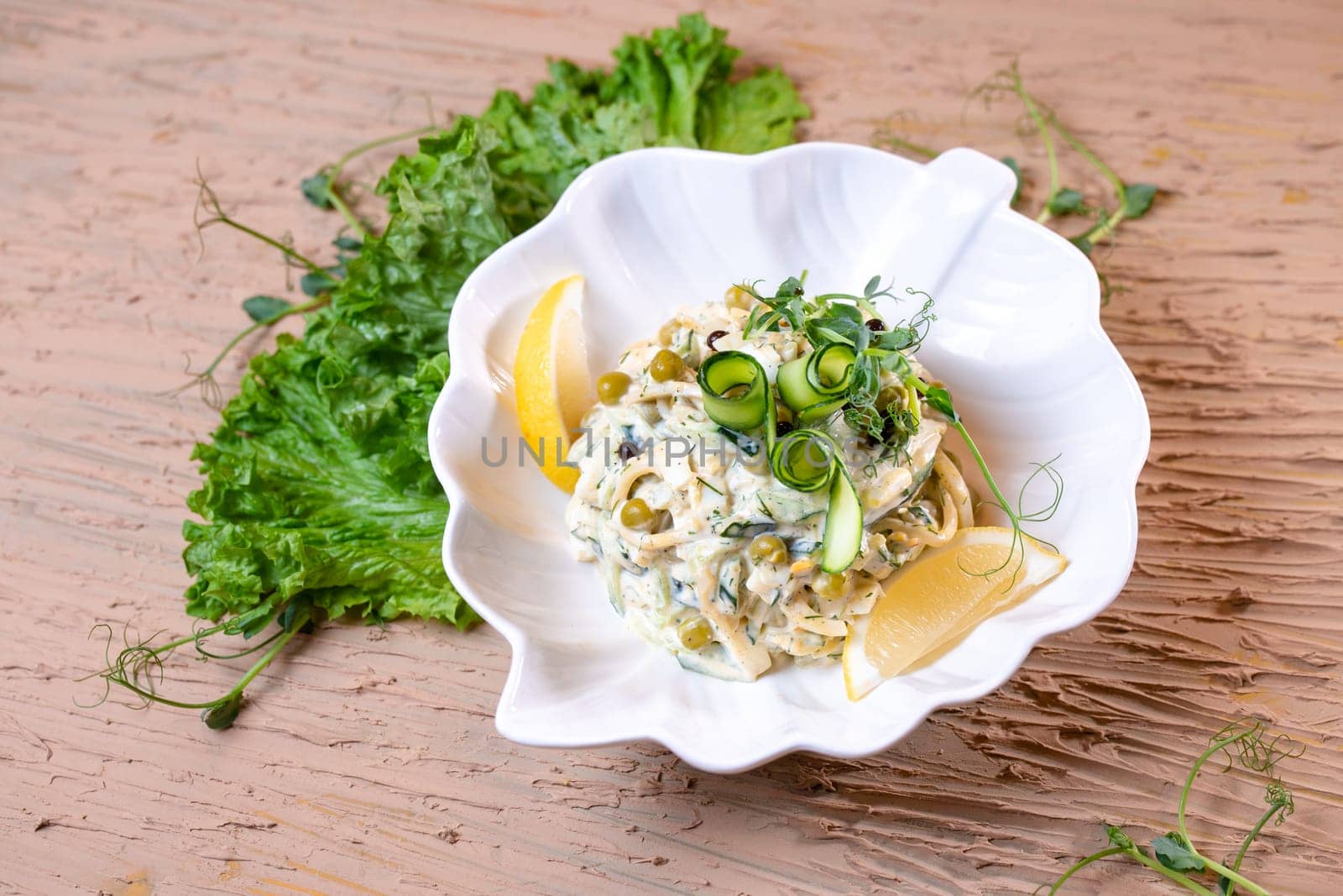 salad with squid rings and peas, with salad in a white plate by Pukhovskiy