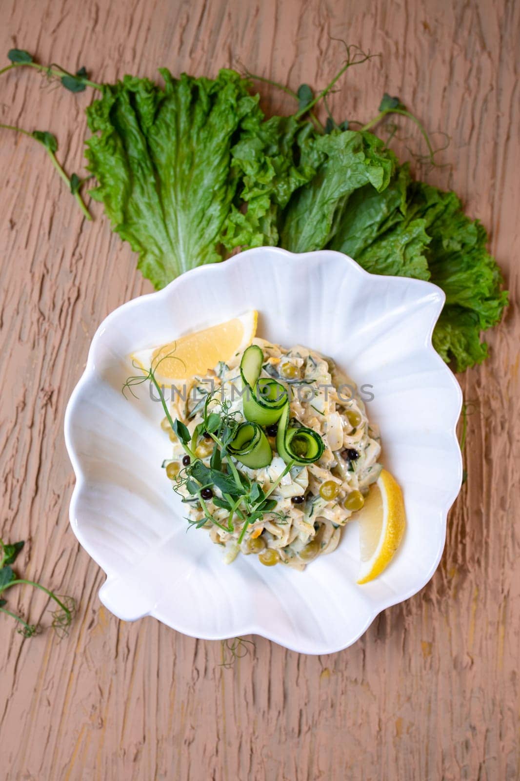 top view salad with squid rings and peas, with salad in a white plate by Pukhovskiy