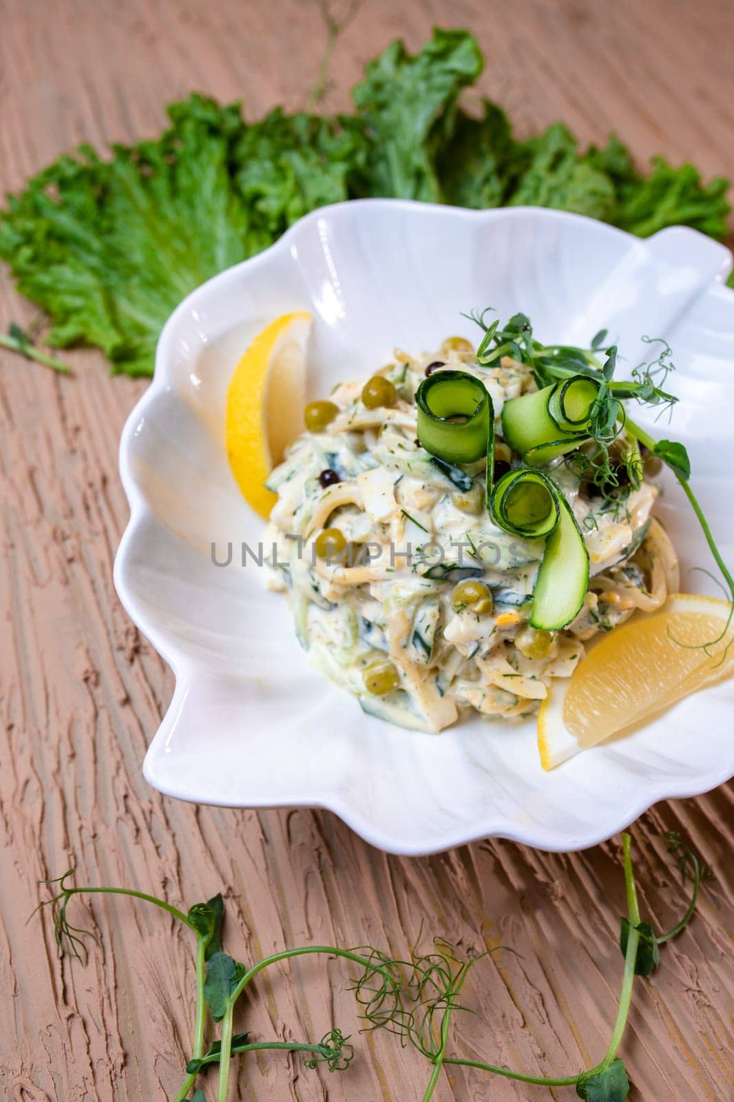 top view salad with squid rings and peas, with salad in a white plate by Pukhovskiy