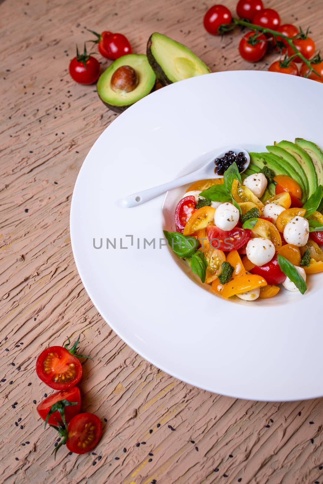 salad with avacado, mozzarella and tomatoes in a white plate by Pukhovskiy