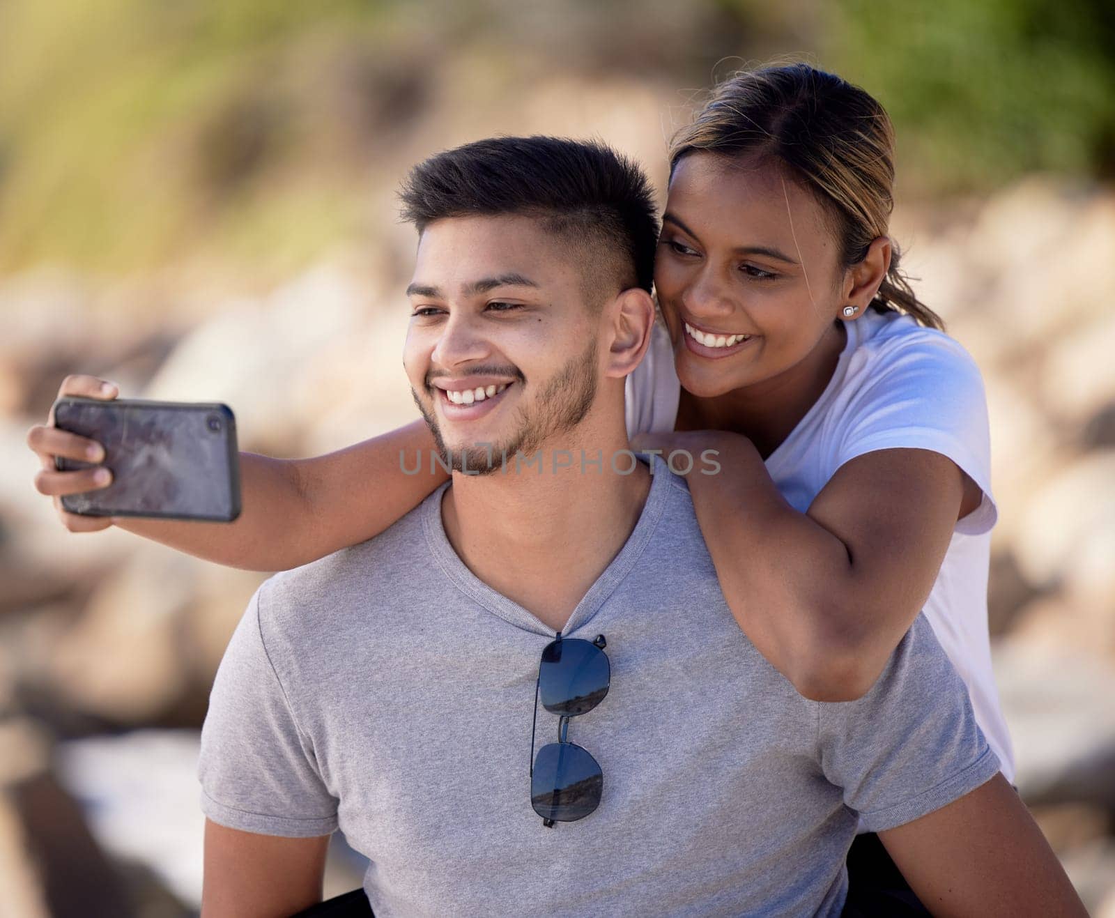 Couple selfie, outdoor nature and hug with smile, care or love by blurred background in sunshine. Man, black woman and smartphone for digital picture with happiness for social media while hiking by YuriArcurs