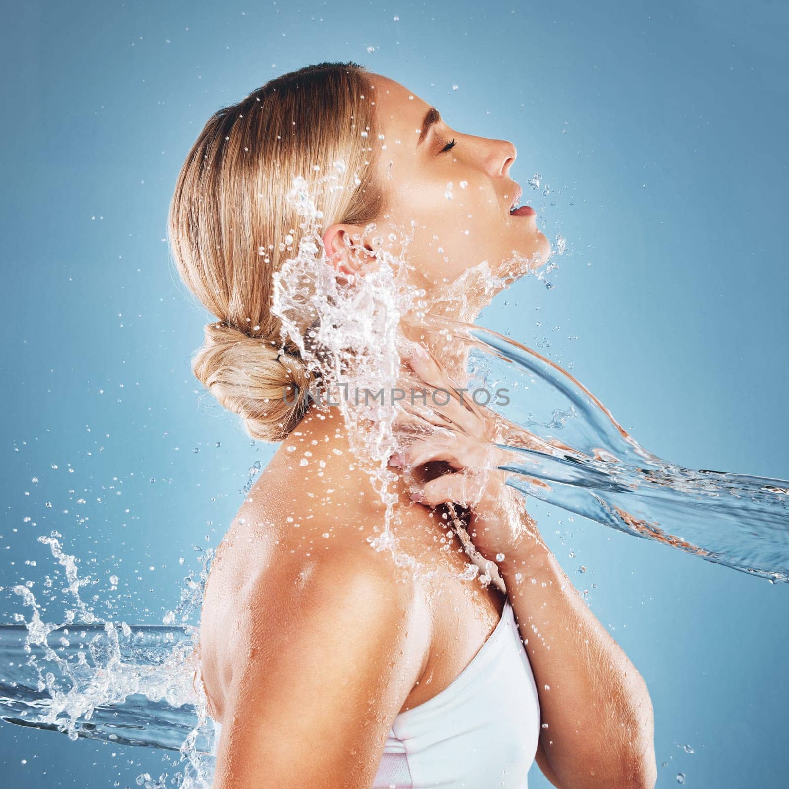 Woman, water and hydration for beauty skincare cosmetics, hygiene or clean moisture against a blue studio background. Female relax in body care cleaning for luxury hydrated skin or cosmetic treatment.