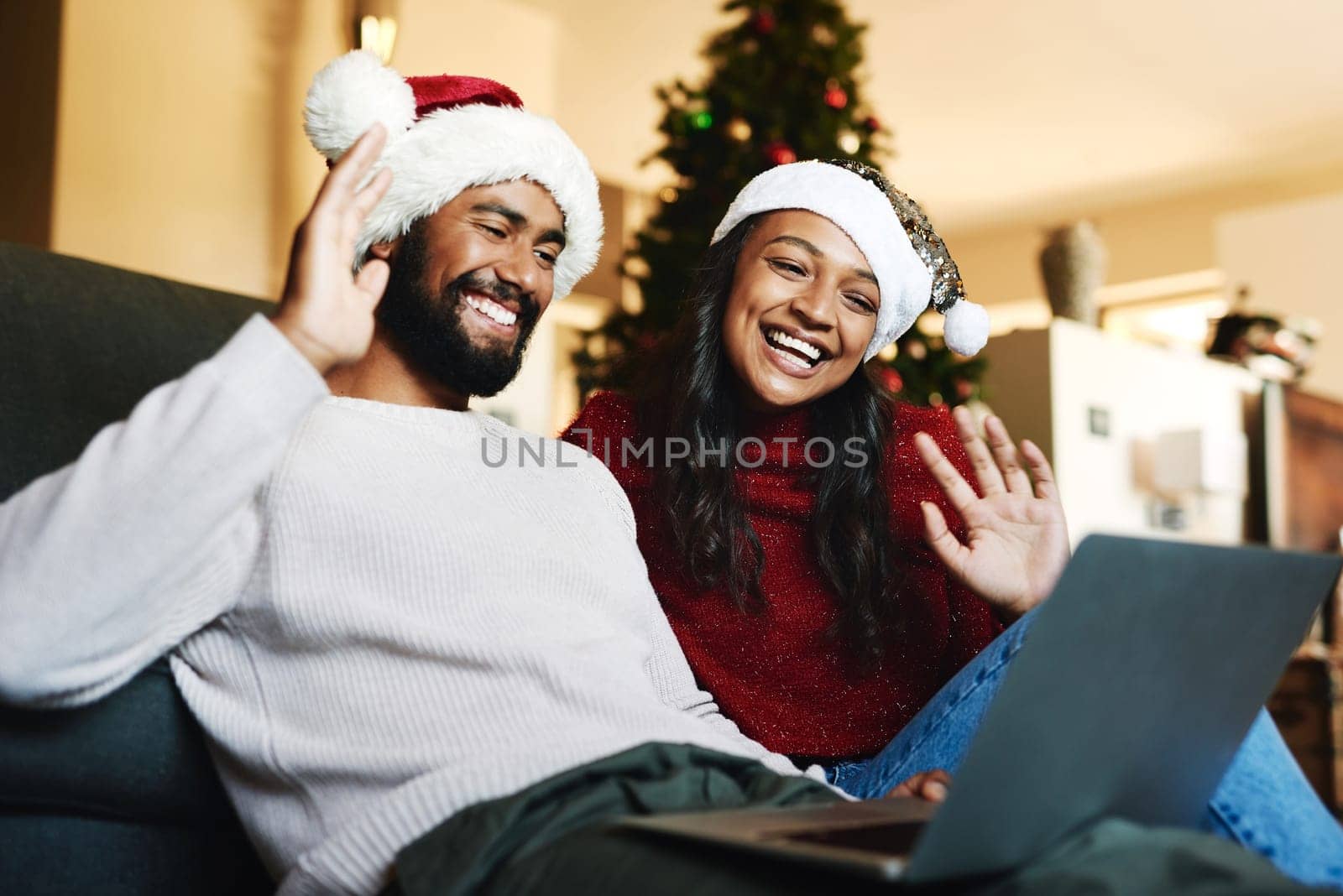 Video call, laptop and Christmas couple on sofa with hello wave for global, international or virtual communication with friends or family. Happy black people on zoom call for holiday celebration chat.