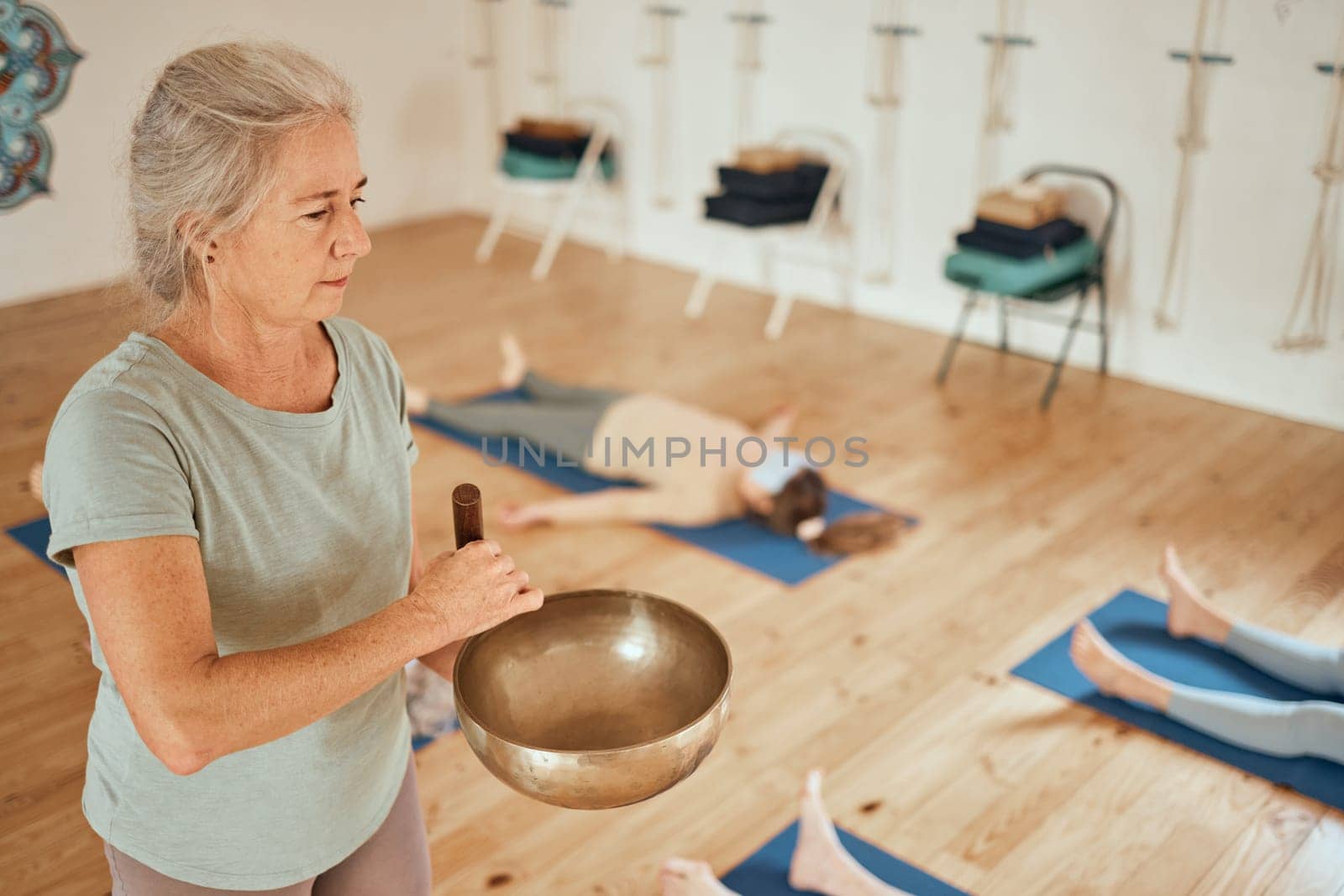 Meditation, class and woman with Tibetan singing bowl for calm, peace and zen in gym studio. Spiritual healing, mindfulness and senior fitness coach in yoga, exercise and pilates lesson for wellness.