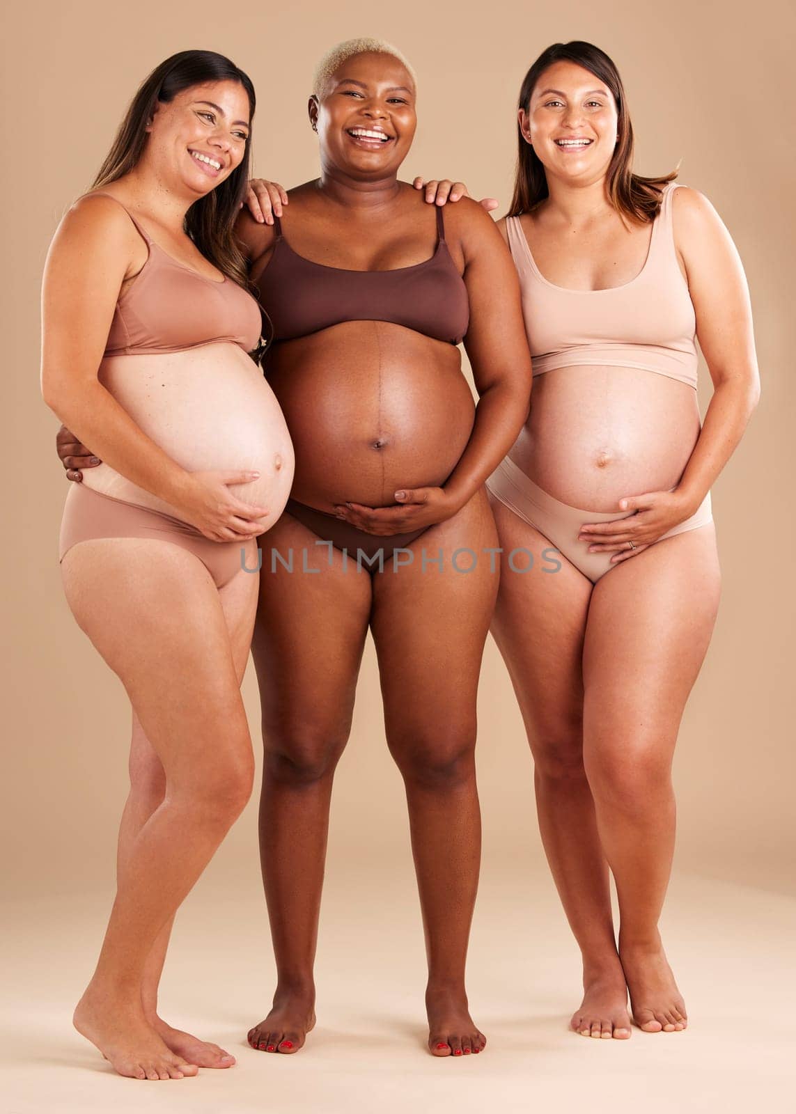 Pregnant, body and portrait of women in belly support touch, hope and community diversity on studio background. Smile, happy and pregnancy friends in underwear, stomach growth and healthcare wellness.