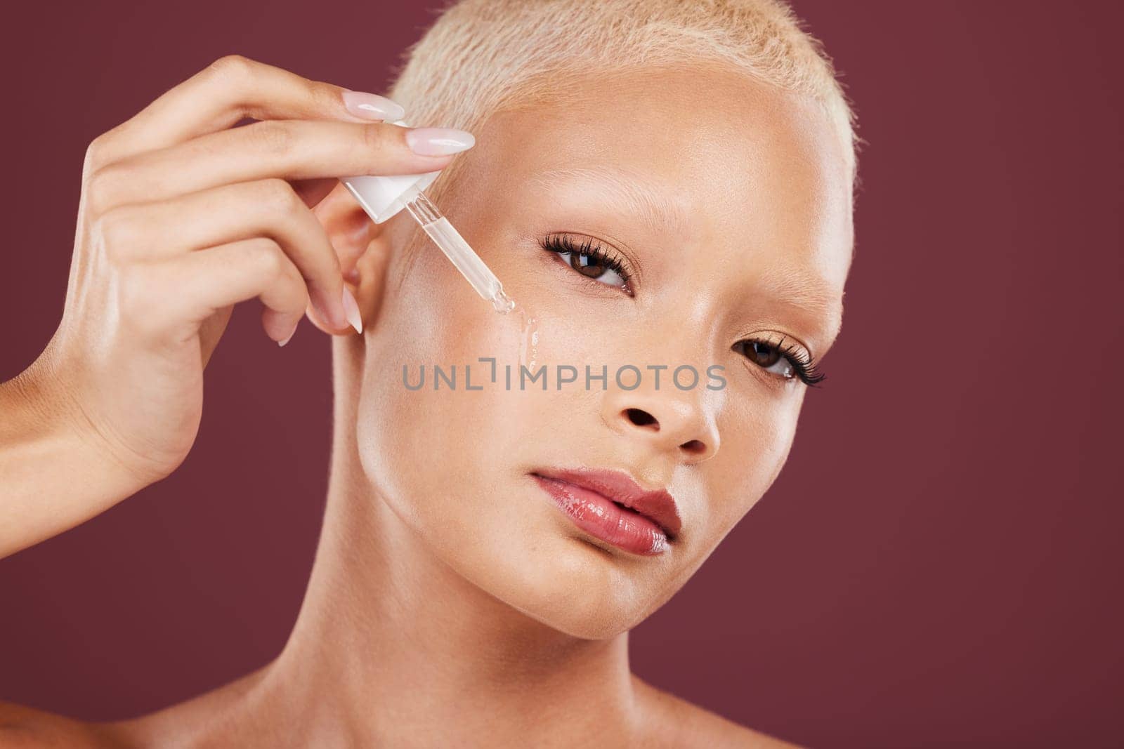 Face skincare, portrait and woman with serum in studio isolated on a red background. Beauty, cosmetics and female model with hydration product, hyaluronic acid or collagen oil for facial treatment. by YuriArcurs