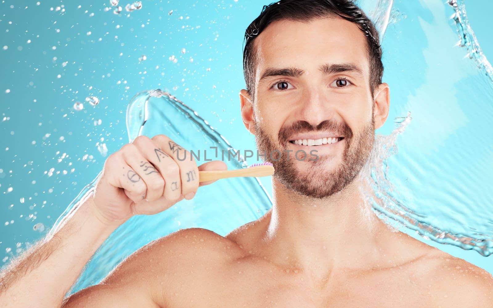 Eco friendly toothbrush, water and portrait of man on blue background for wellness, hygiene and brushing teeth. Cleaning, dental and face of male with toothpaste for grooming, whitening and health by YuriArcurs