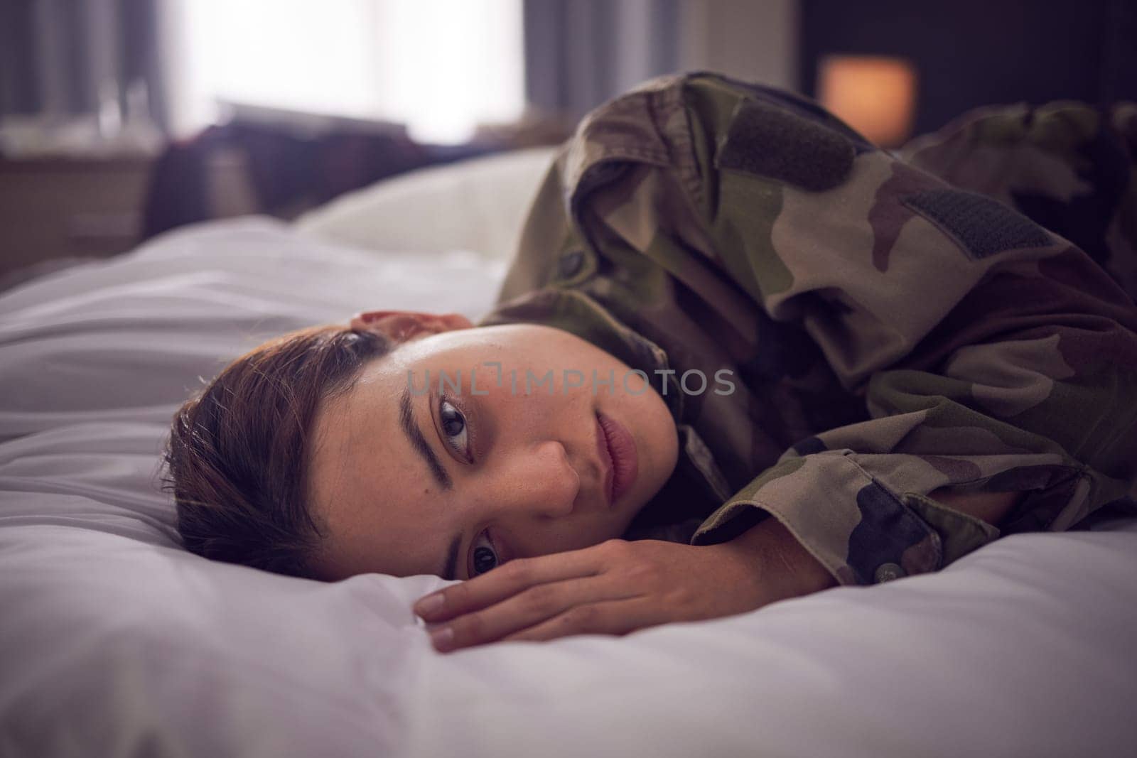 Depressed female soldiers in mental health issues, sleepless or nightmare in the bedroom. Woman, stress and depression lying on bed in military suffering from insomnia or mental disorder at home. by YuriArcurs