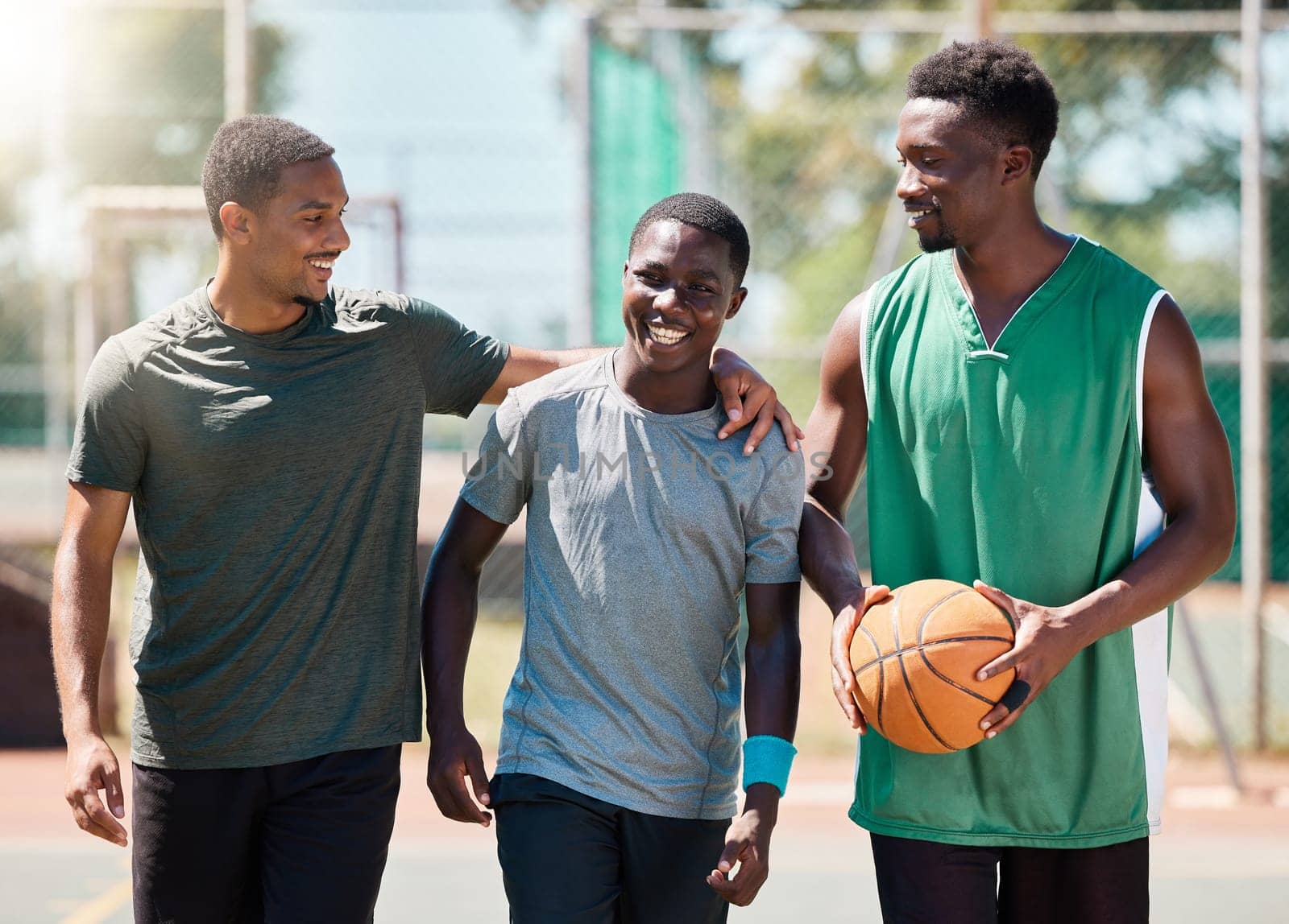 Basketball player, happy friends and walking together in conversation, training or exercise in summer. Team happiness, basketball court and basketball for black man group, outdoor or game in sunshine.