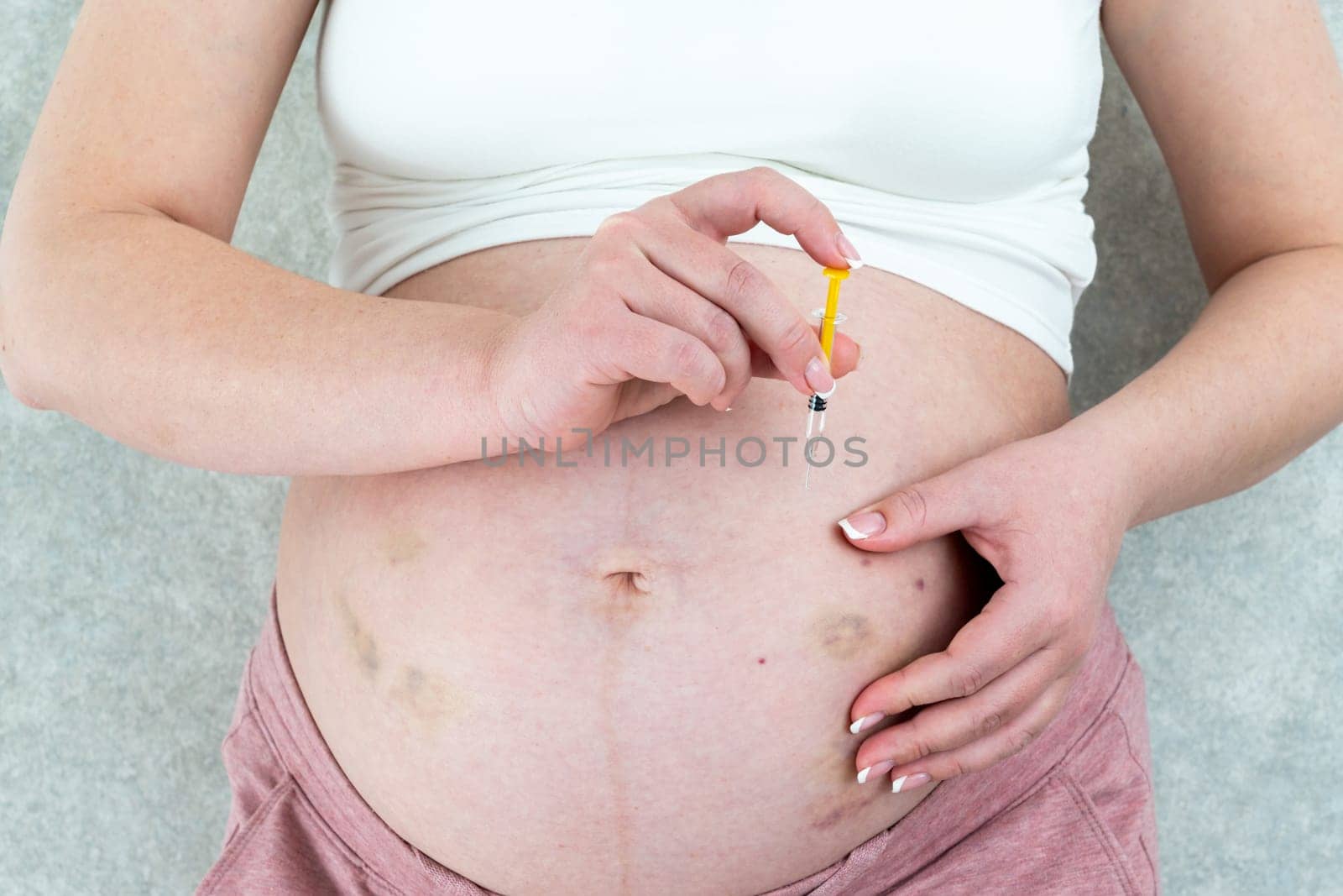 Blood thinners concept. Pregnant woman making injection in her belly