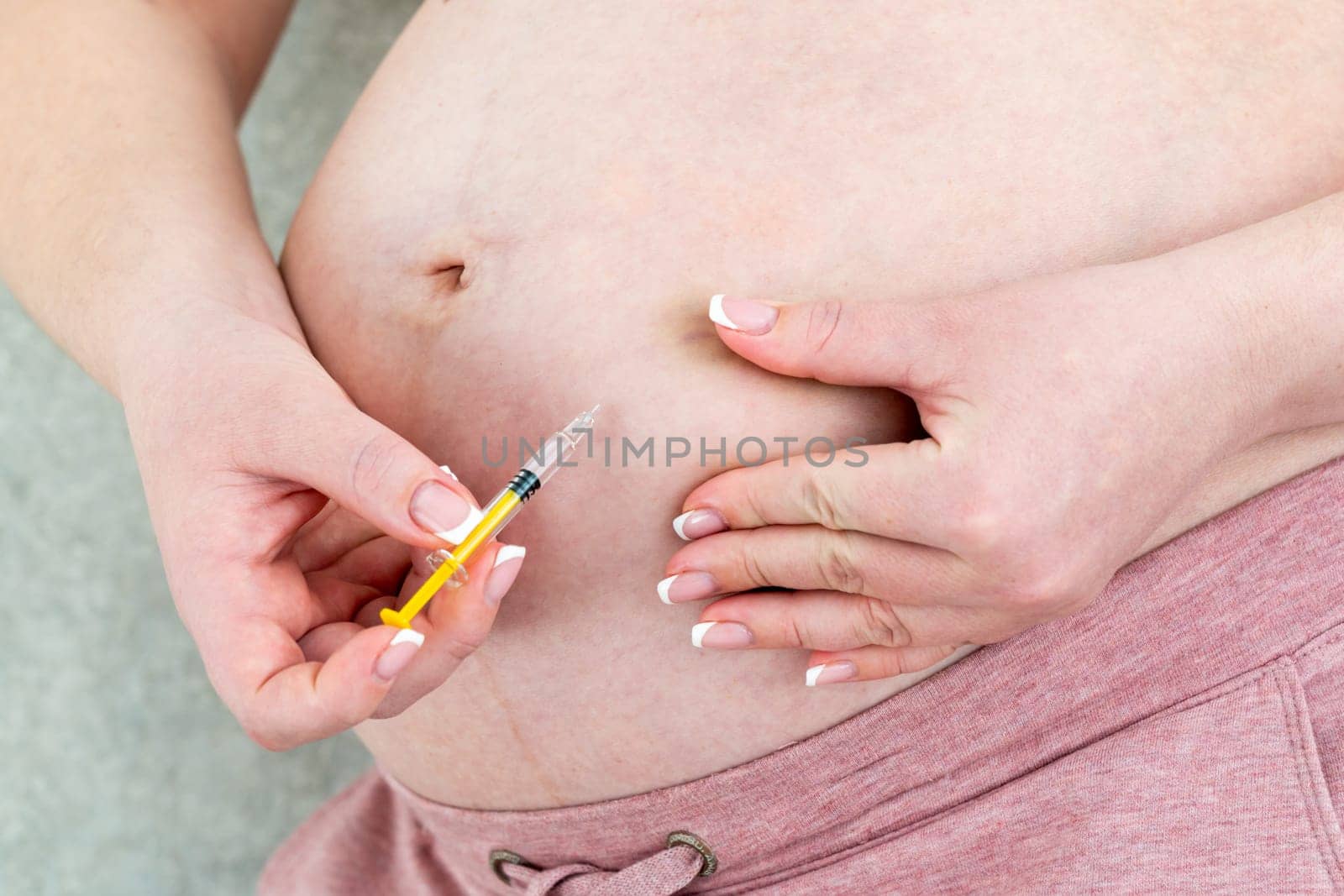 Blood thinners concept. Close up of Pregnant woman making injection in stomach by Mariakray