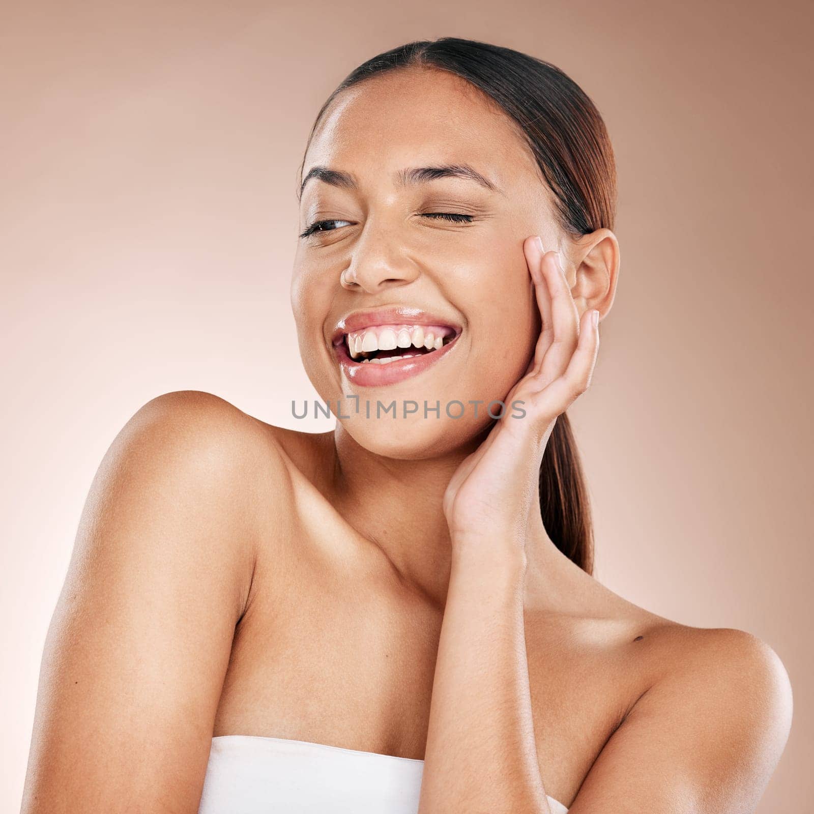 Skincare, beauty and happiness, woman with smile laughing on studio background at fun spa. Makeup, glamour and wink, luxury skin care with hands on face, natural detox facial massage on happy woman. by YuriArcurs