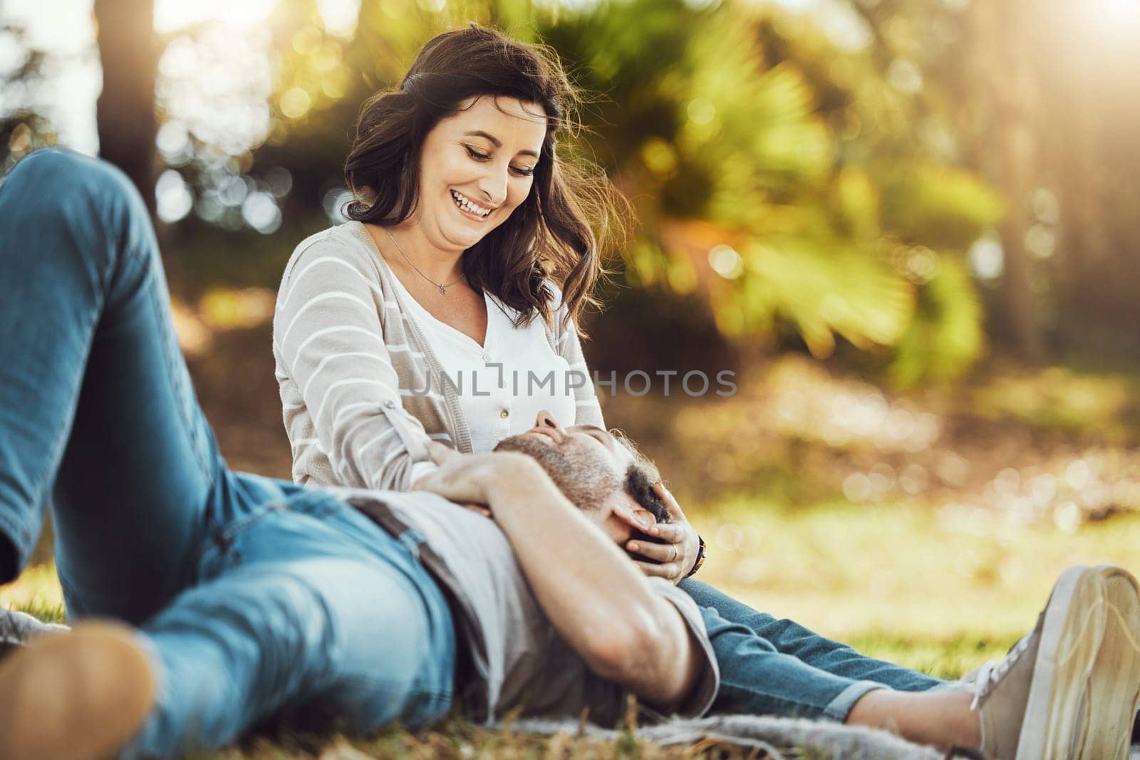 Love, relax and couple at park, laughing at funny joke or comic comedy and having fun together outdoors. Valentines day, romance cuddle and care of man lying on lap of happy woman on romantic date. by YuriArcurs