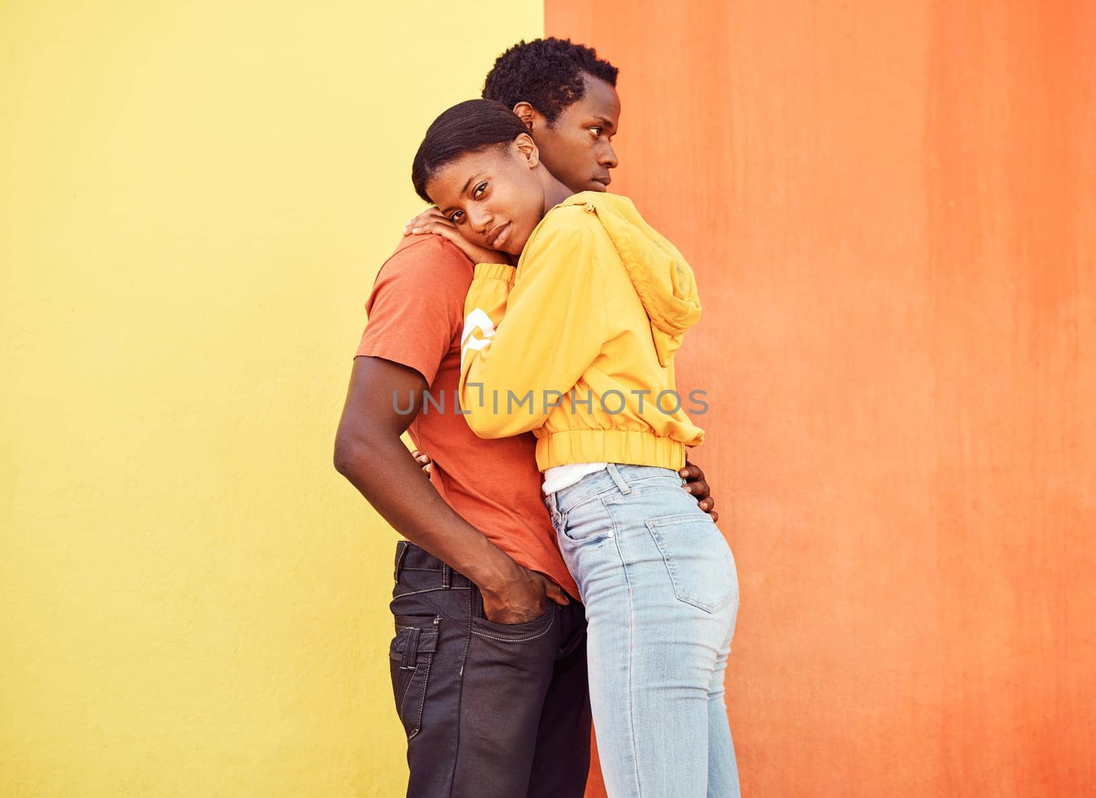 Love, hug and comfort with a black couple together outside on a color wall background for romance or dating. Hugging, date and consoling with a man and woman holding each other in support or care by YuriArcurs